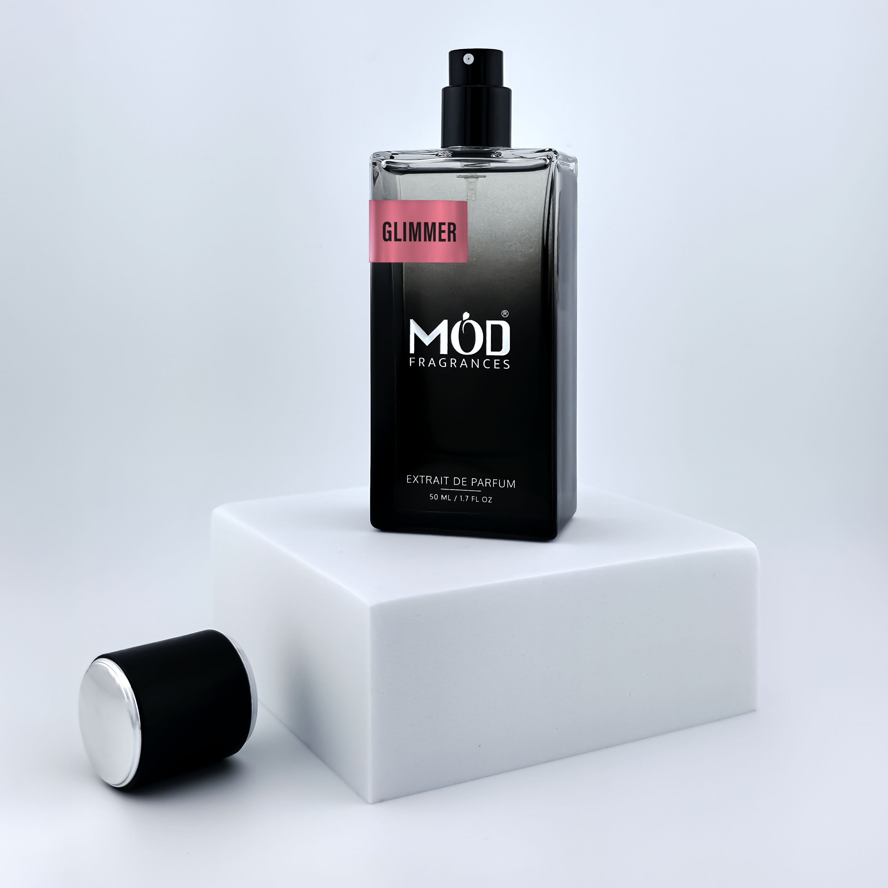 Perfume bottle labeled 'Glimmer' by Möd Fragrances on a white platform with a light gray background