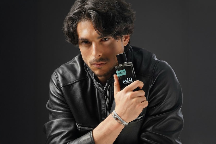 Man holding a perfume bottle with a dark background