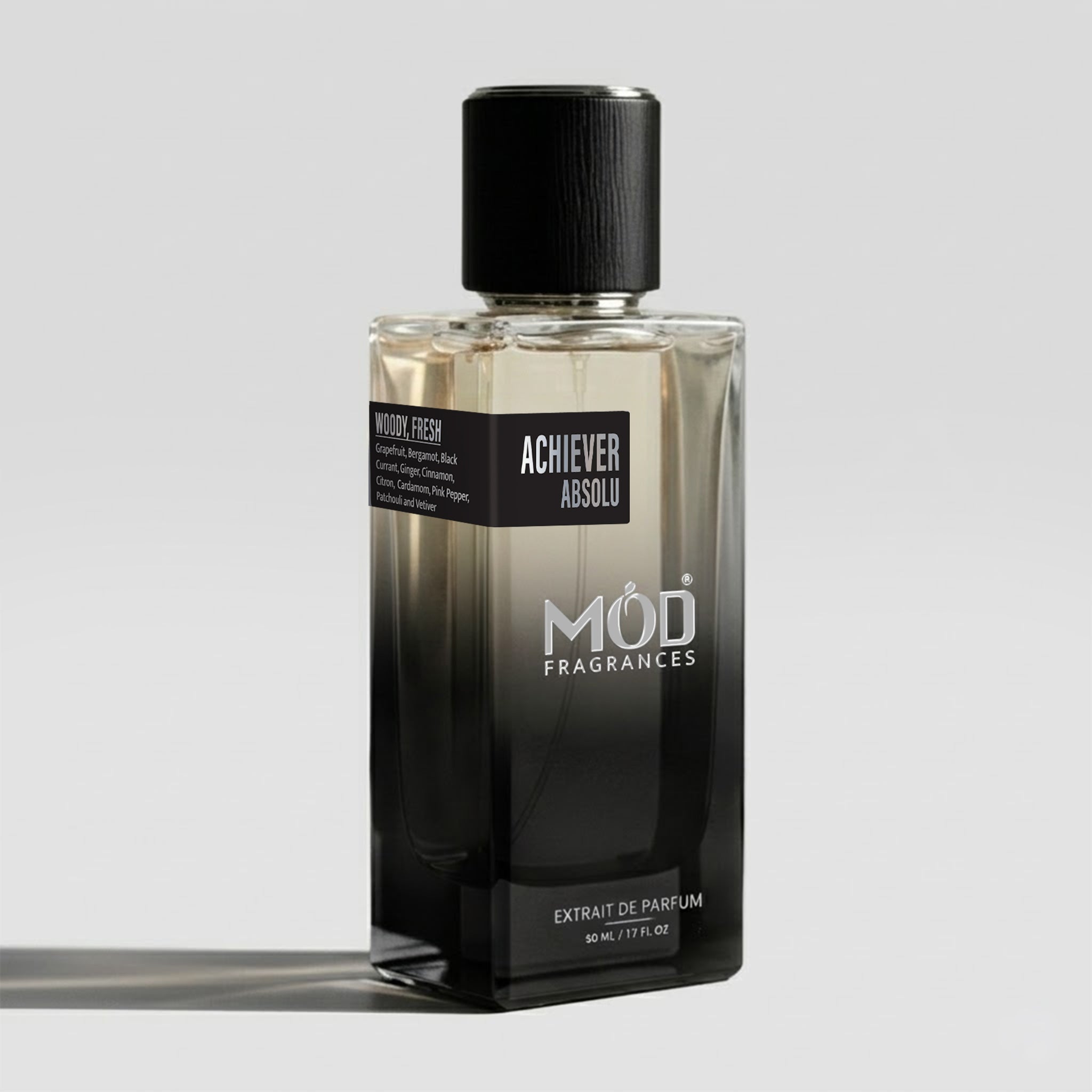 A rectangular glass perfume bottle by MOD Fragrances, labeled “Achiever Absolu” with a small label detailing its notes, stands on a light background.