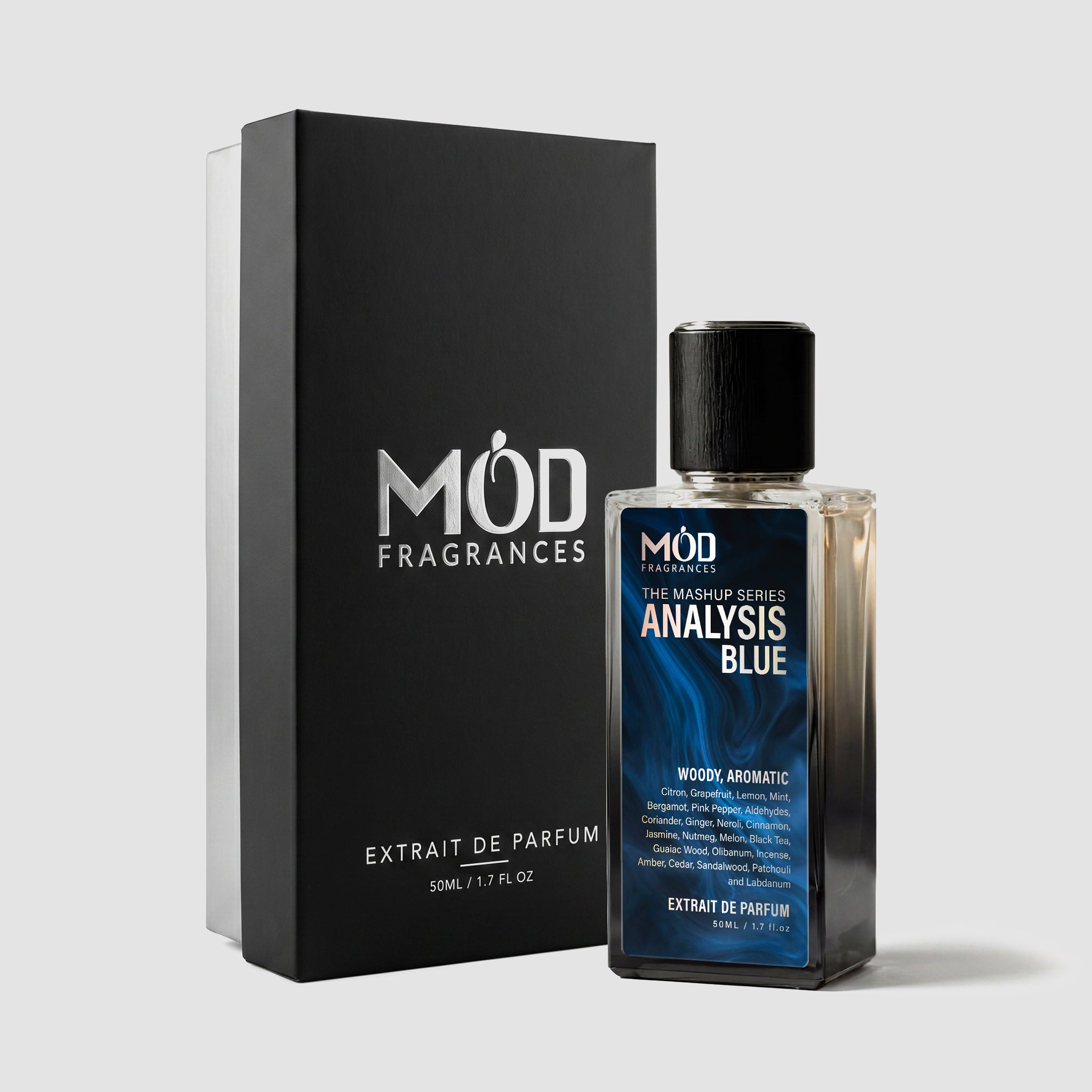 A rectangular perfume bottle by MOD Fragrances, labeled "mashup series Analysis Blue" is positioned next to its closed, upright black display box on a light grey background.