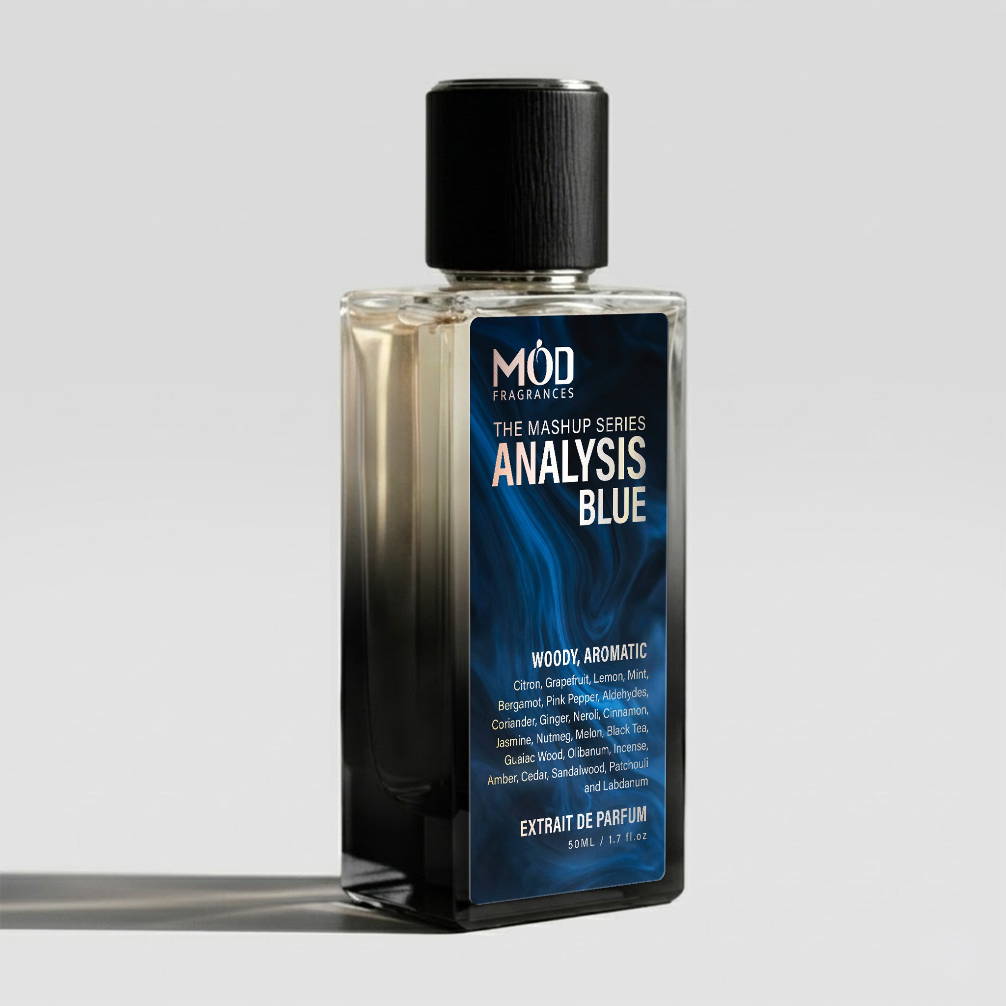 A rectangular glass perfume bottle by MOD Fragrances, labeled "Mashup series Analysis Blue" with a large label detailing its fresh, woody, aromatic notes, stands on a light background.
