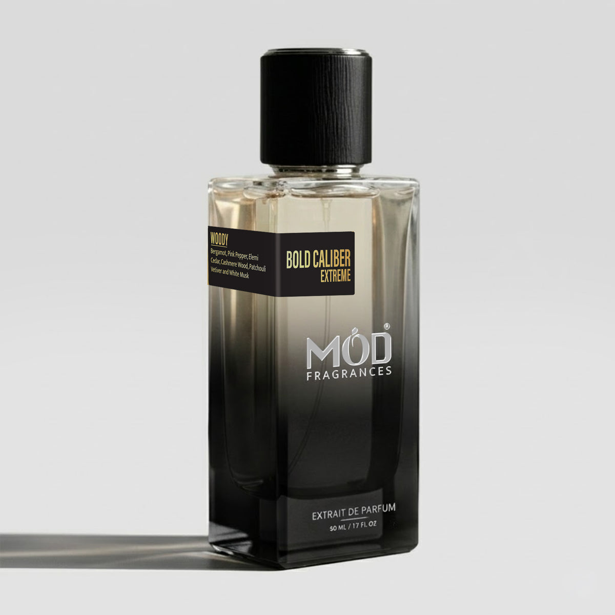 A rectangular glass perfume bottle by MOD Fragrances, labeled “Bold Caliber Extreme” with a small label detailing its notes, stands on a light background.