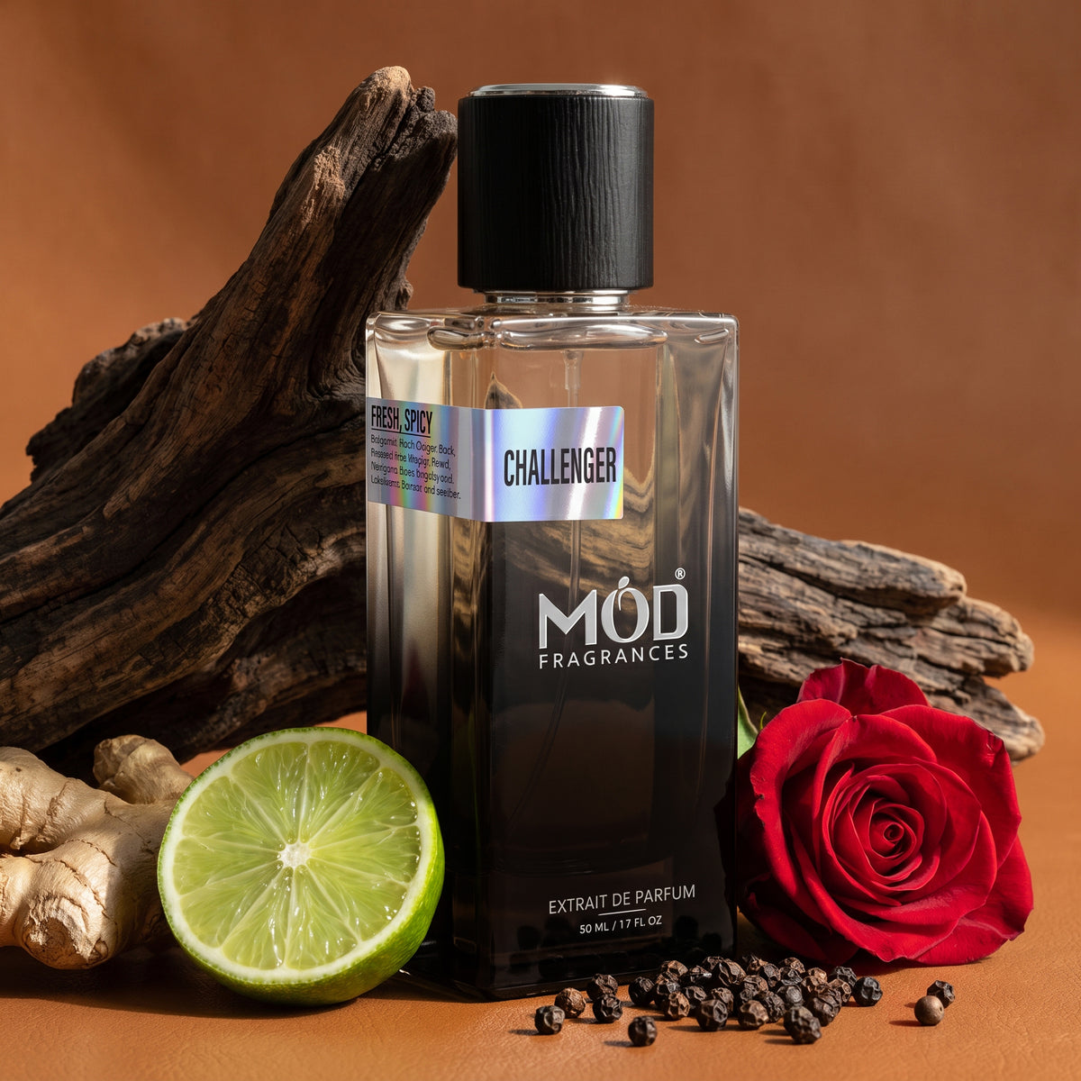 A bottle of MOD Fragrances Challenger Extrait de Parfum, styled with a fresh lime half, ginger root, black peppercorns, and a red rose on a warm brown background.