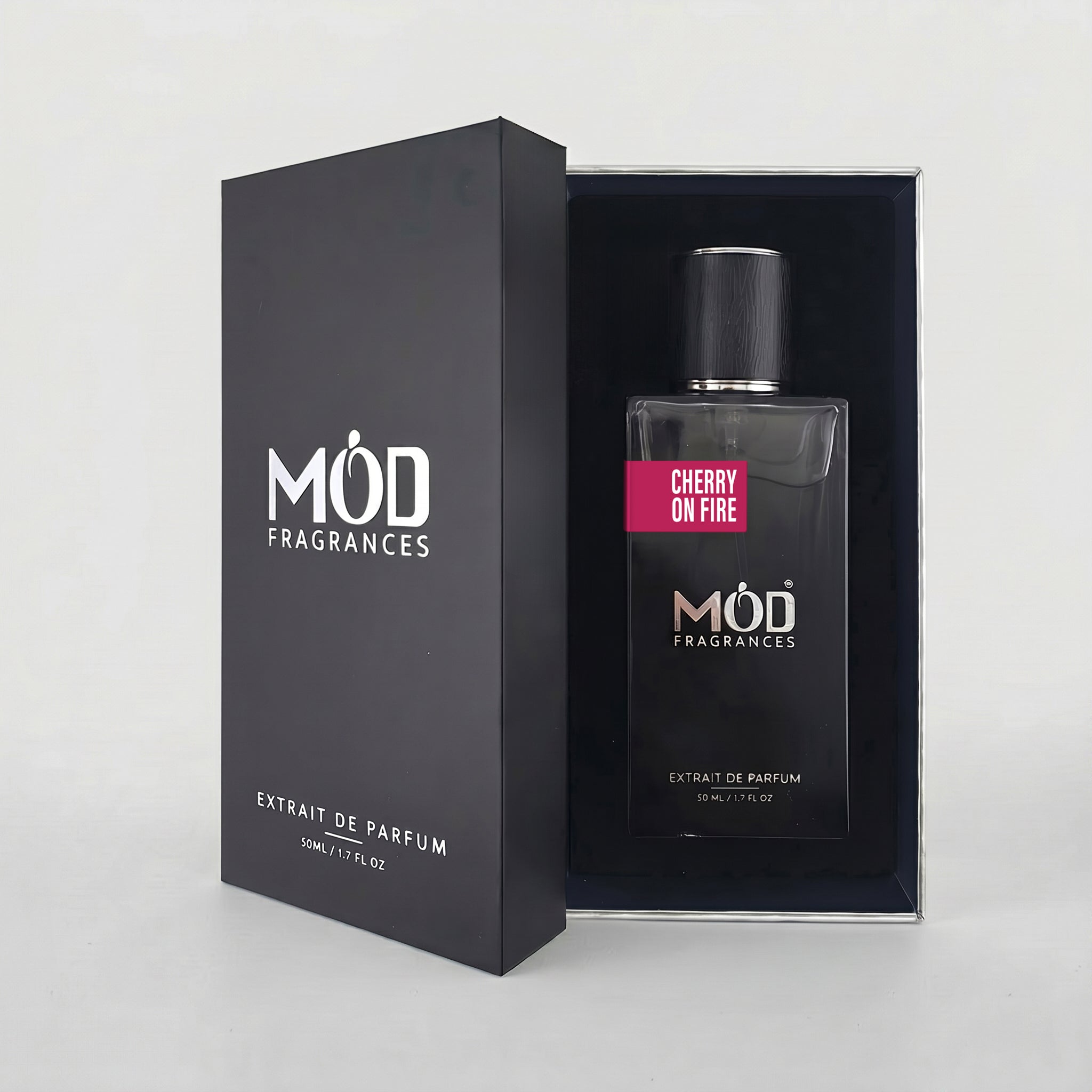 An open premium black perfume box reveals a rectangular glass bottle labeled “Cherry on Fire” by MOD Fragrances, resting securely in a black-lined presentation case.