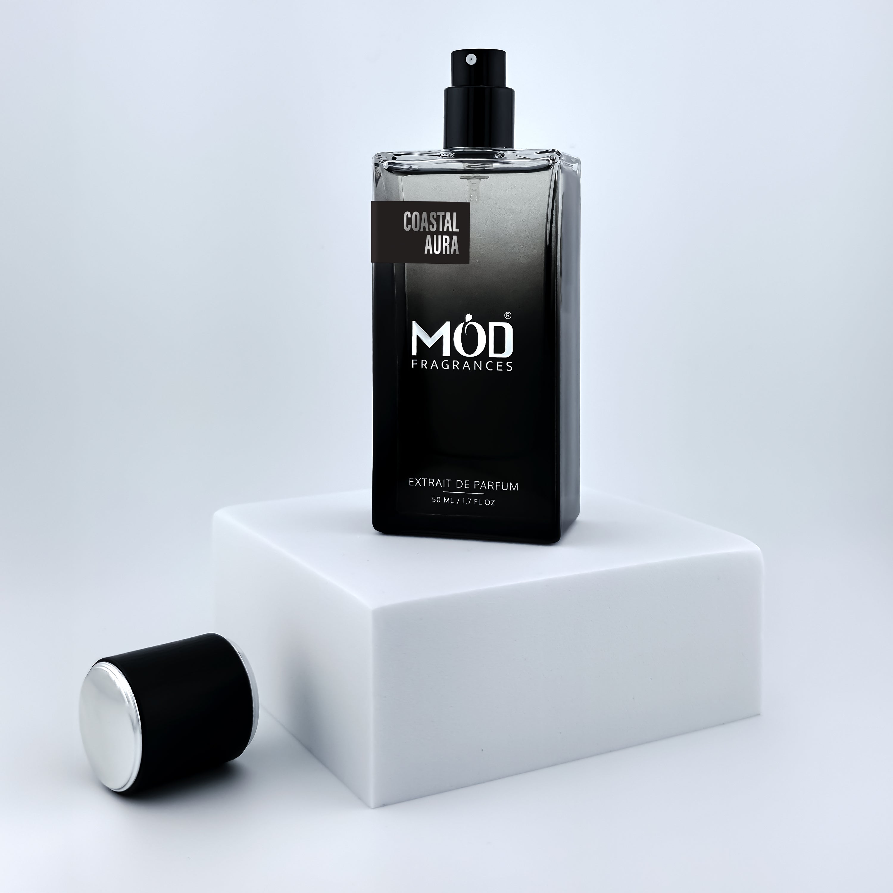 Perfume bottle with black cap on a white platform against a light gray background