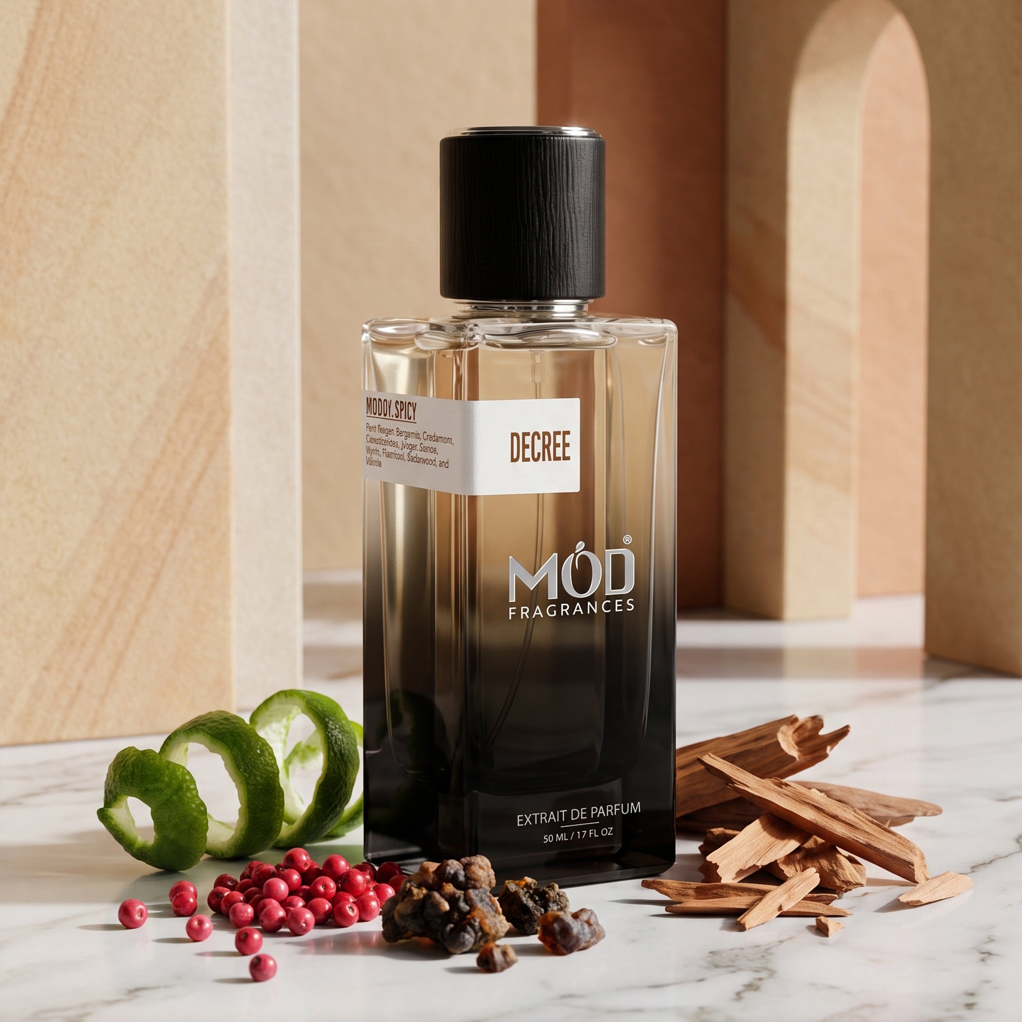 A bottle of Decree by Mod Fragrances 'Woodsy Spice' extrait de parfum stands on a marble surface surrounded by its scent ingredients, including green citrus slices, red berries, cinnamon sticks, and cloves, with a warm beige architectural background.