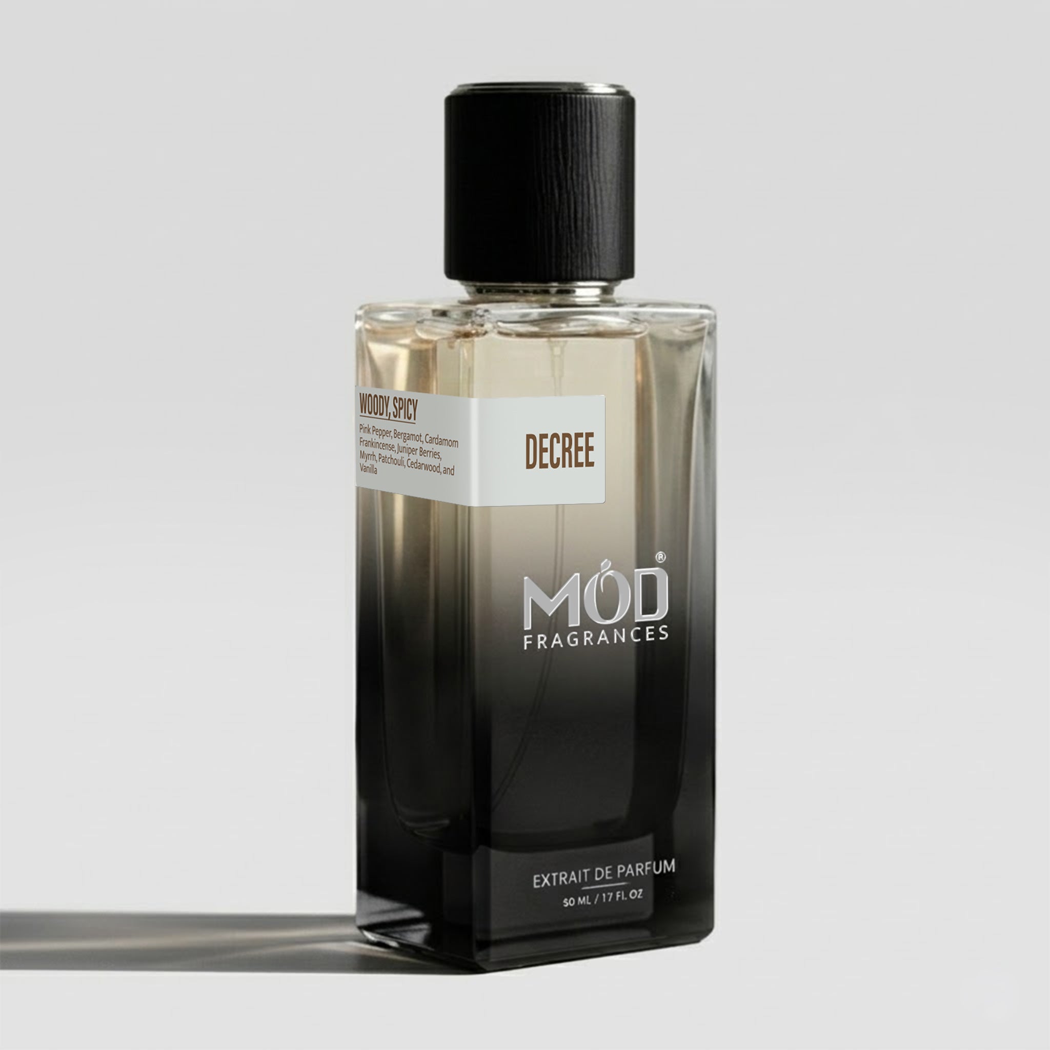 A bottle of Decree by Mod Fragrances Extrait de Parfum, featuring a black-to-clear gradient glass bottle with a textured black cap, set against a light gray background.