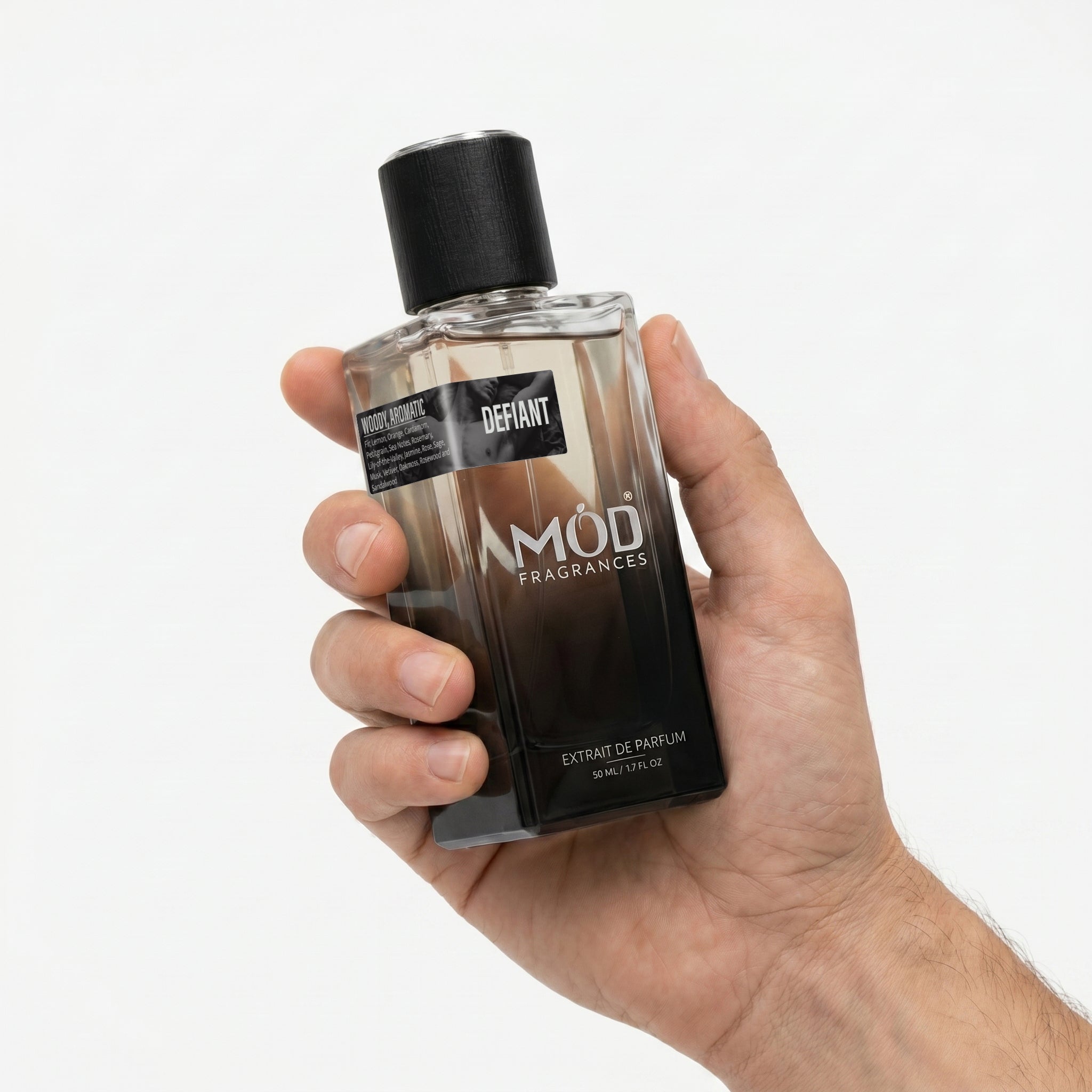 A hand holding a bottle of Mod Fragrances Defiant Extrait de Parfum against a clean white background.