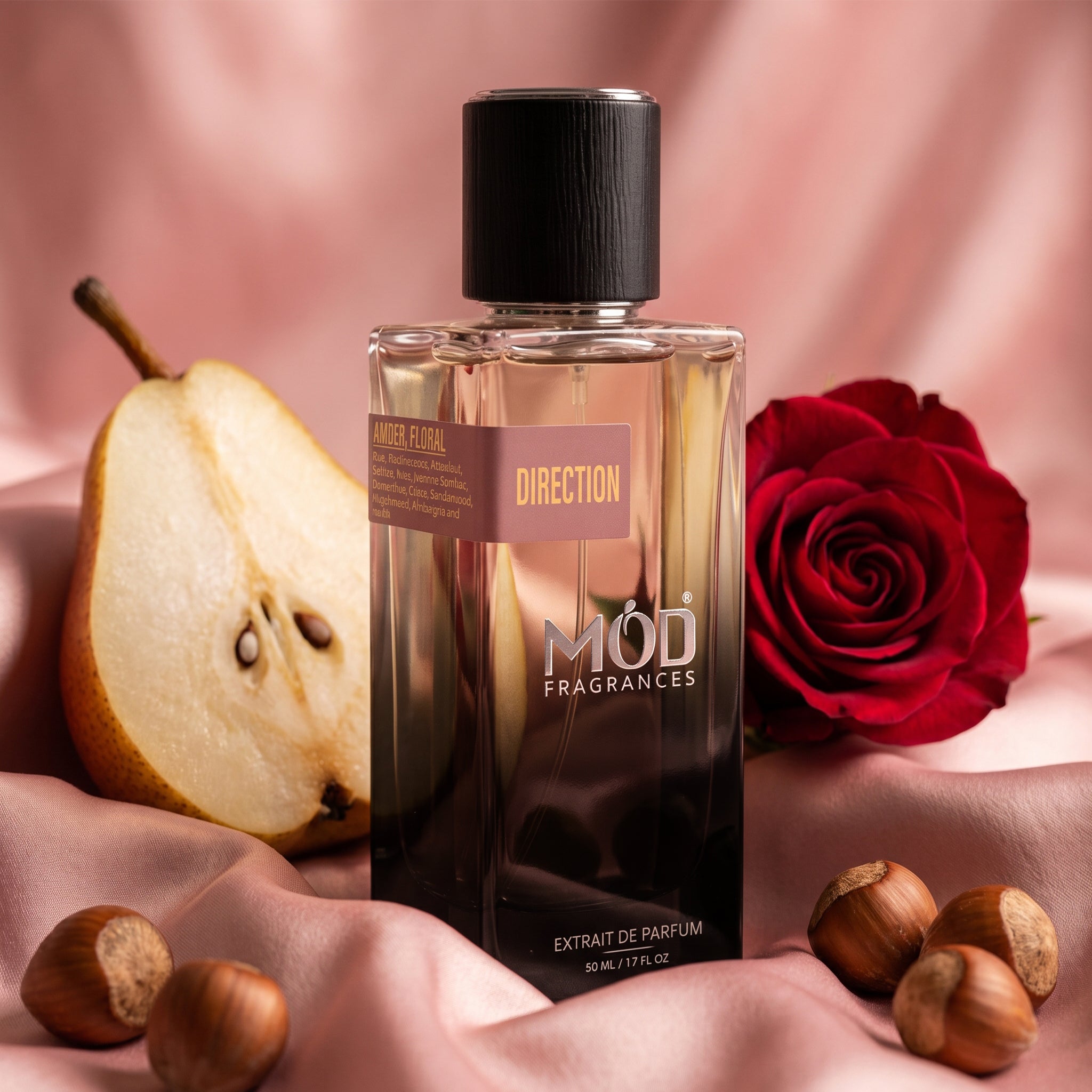 Perfume bottle labeled 'Möd Fragrances' with a pear, rose, and hazelnuts on a pink fabric background