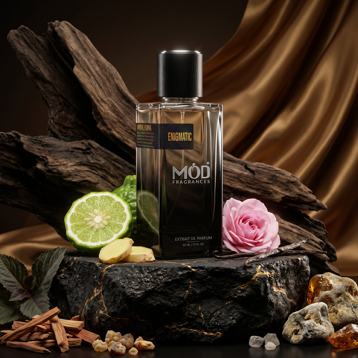 A rectangular glass perfume bottle by MOD Fragrances, labeled "Enigmatic” is standing upright on sea sand surrounded by its ingredients like Ginger, Bergamot, Pink Pepper, Green Notes, Cardamom, Black Currant, pink Turkish Rose, Vanilla, Benzoin, Sandalwood, Cedar, Patchouli, Musk and Ambergris., on black stone with golden veins in dark room, with light brown golden silk cloth and big driftwood in the background, highlighting bottle and its ingredients.