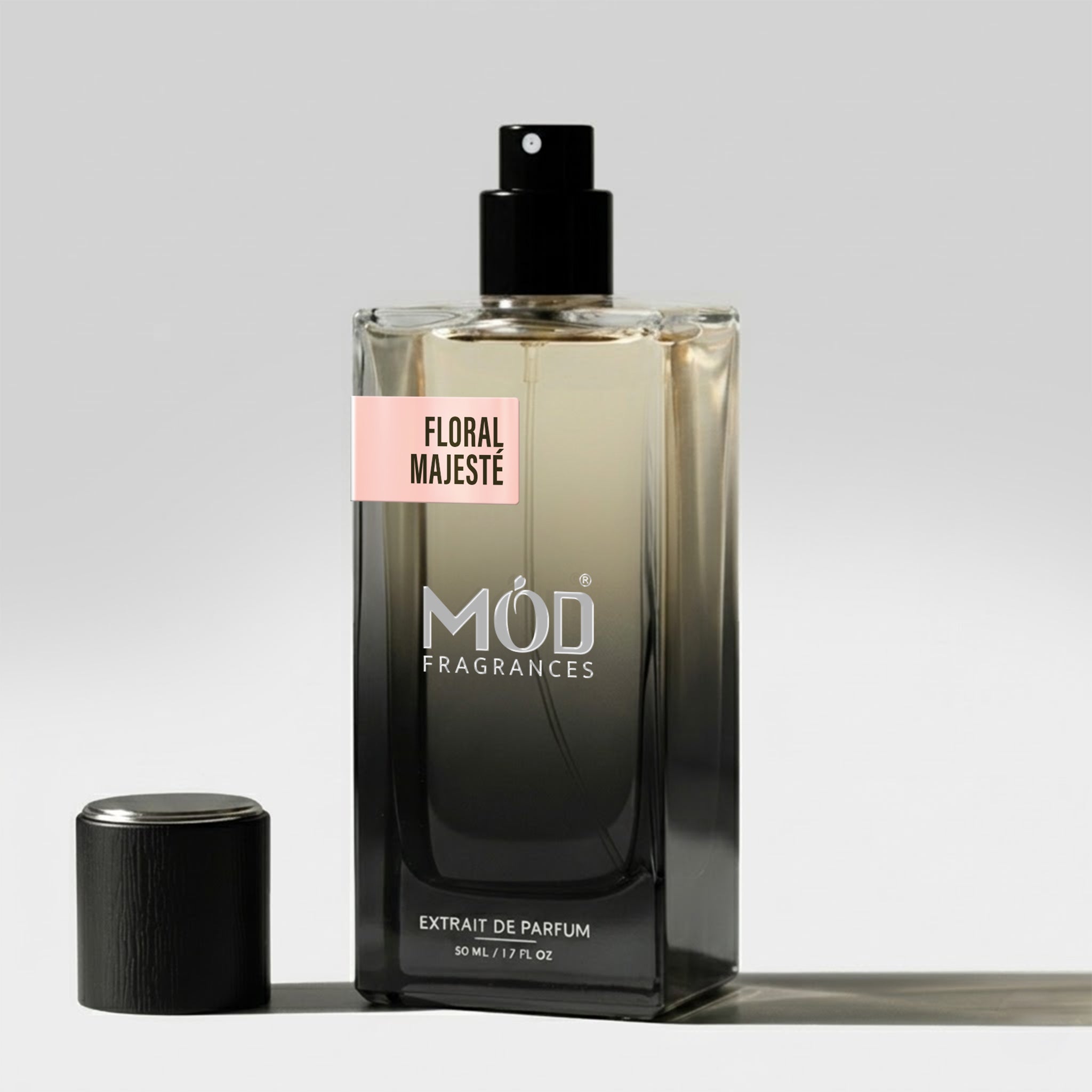 A rectangular glass perfume bottle by MOD Fragrances, labeled "Floral Majeste” stands on a light surface with its black cap placed beside it.