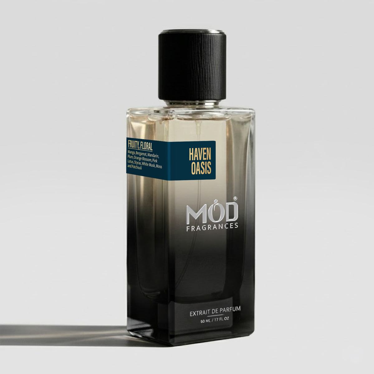 Inspired by Torino 24. A rectangular glass bottle of MOD Fragrances Haven Oasis Extrait de Parfum with a black cap and a black-to-clear gradient design, featuring a dark teal label with gold text, set against a light gray background.