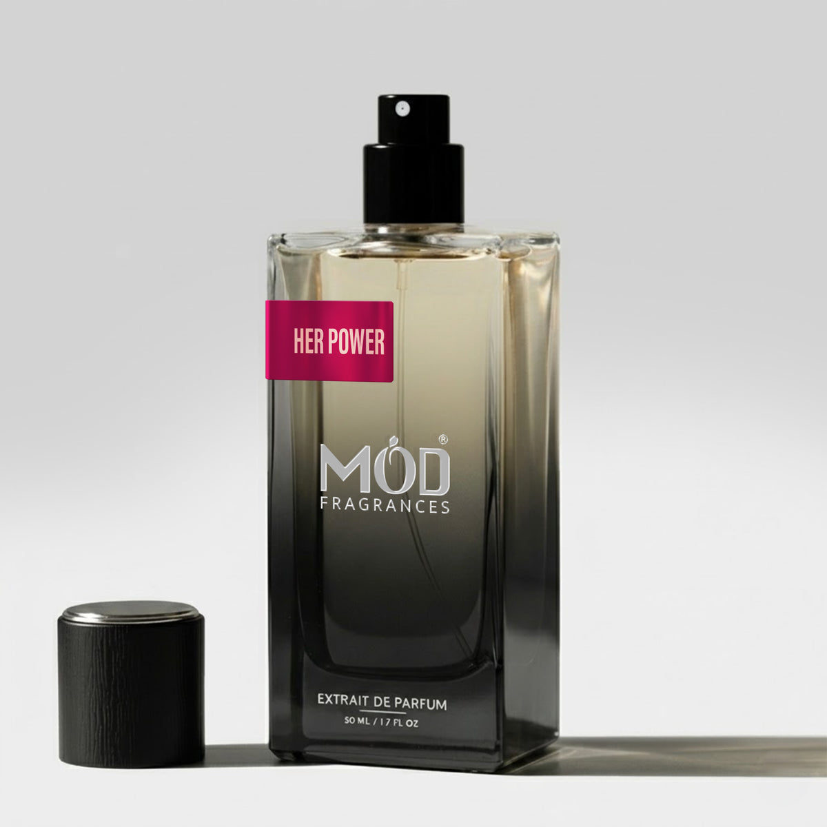 A bottle of MOD FRAGRANCES 'Her Power' extrait de parfum with a black spray top and a pink label, shown next to its black cap on a light gray background.