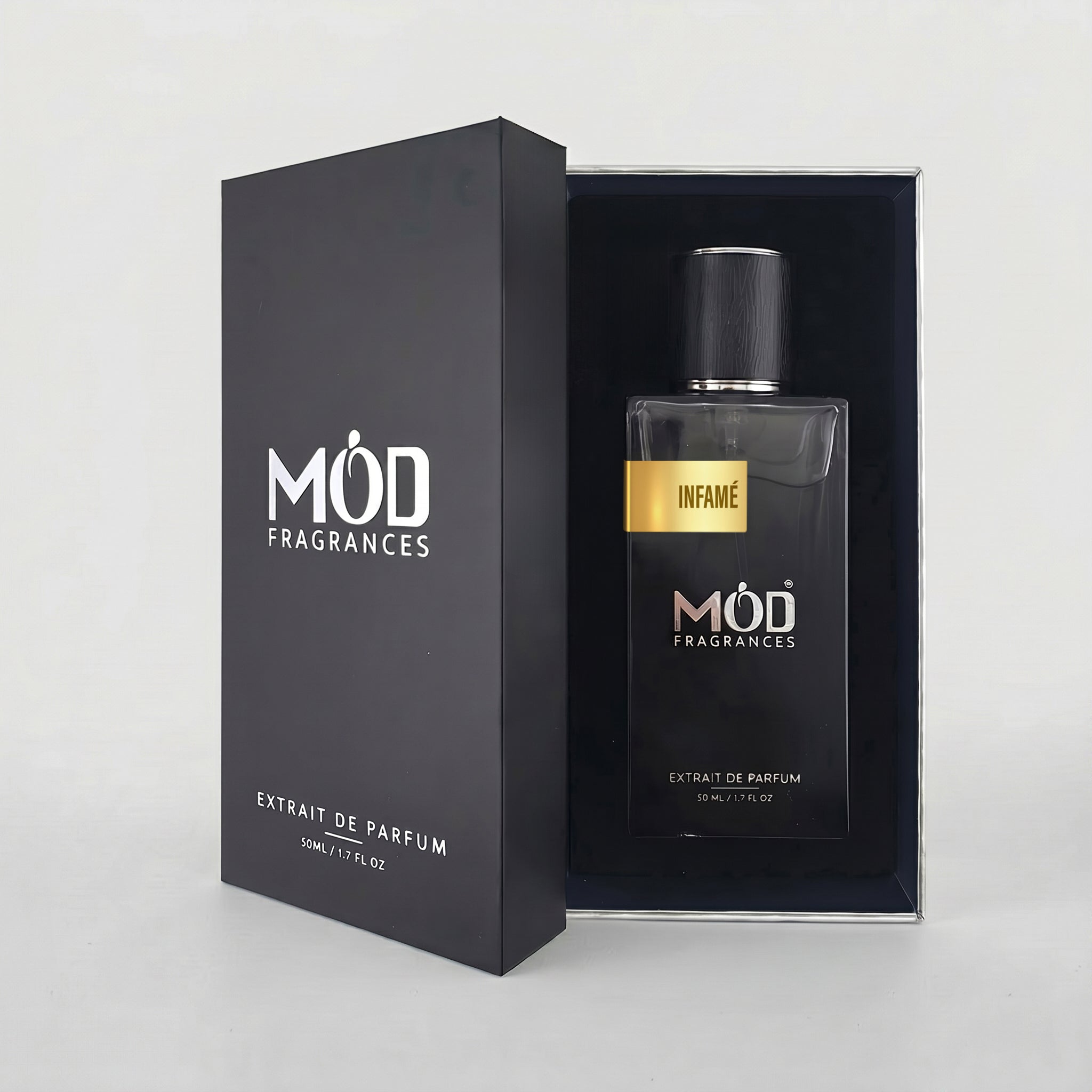 An open premium black perfume box reveals a rectangular glass bottle labeled “Infame” by MOD Fragrances, resting securely in a black-lined presentation case.