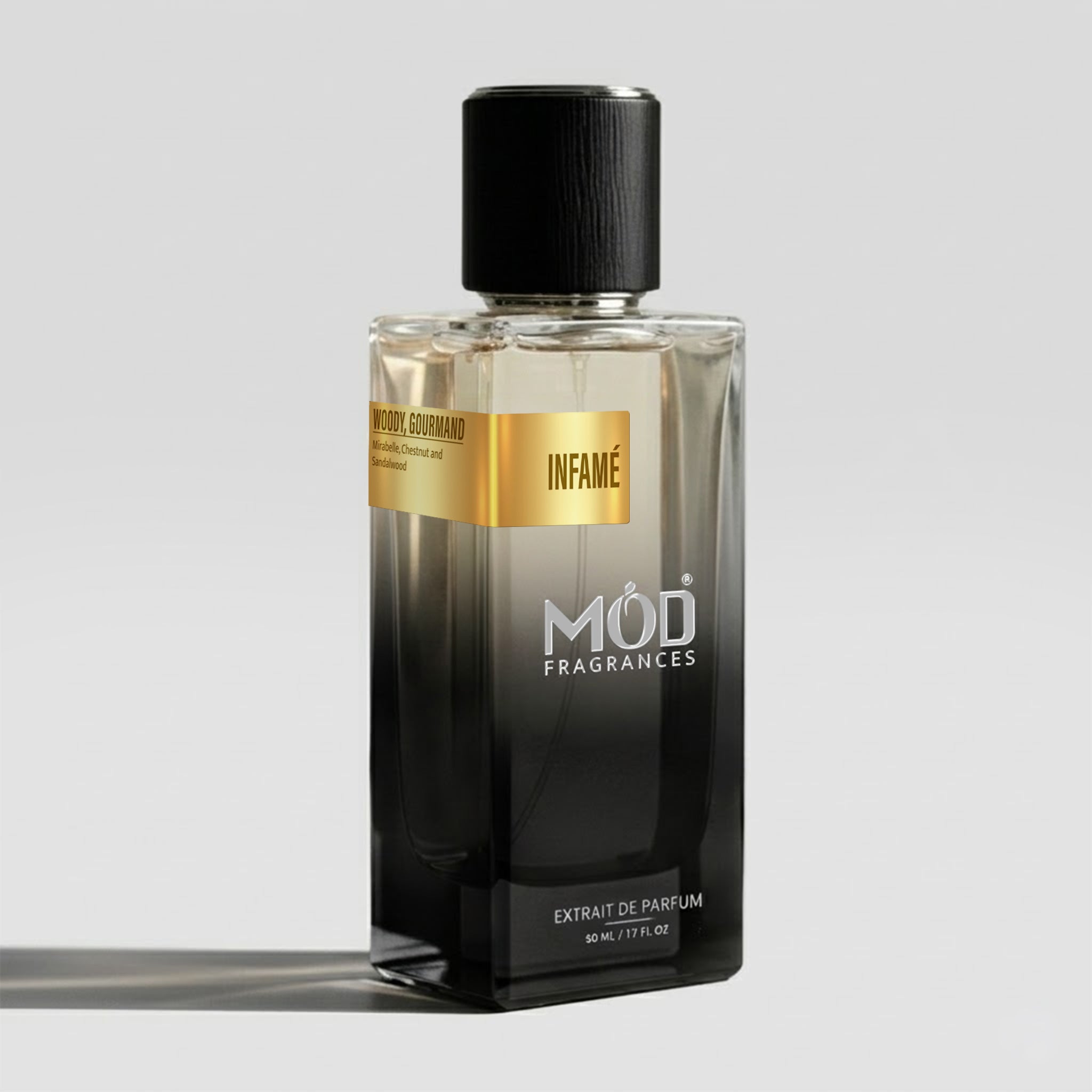 A rectangular glass perfume bottle by MOD Fragrances, labeled “Infame” with a small label detailing its notes, stands on a light background.