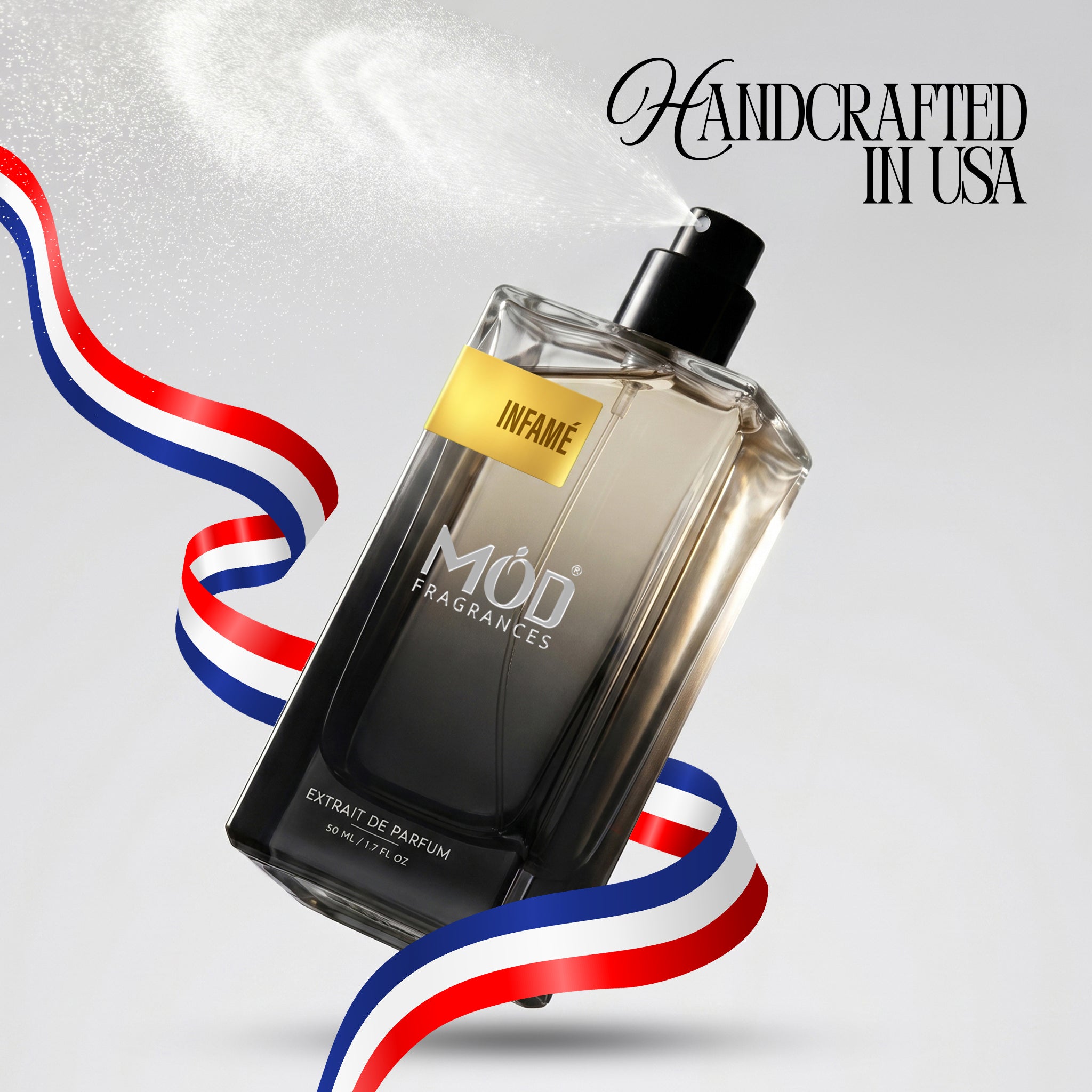 A rectangular glass perfume bottle by MOD Fragrances, labeled "Infame” is captured mid-spray with a fine mist dispersing into the air, accented by stylized red, white, and blue ribbons, with the text "Handcrafted in USA" in the upper right.