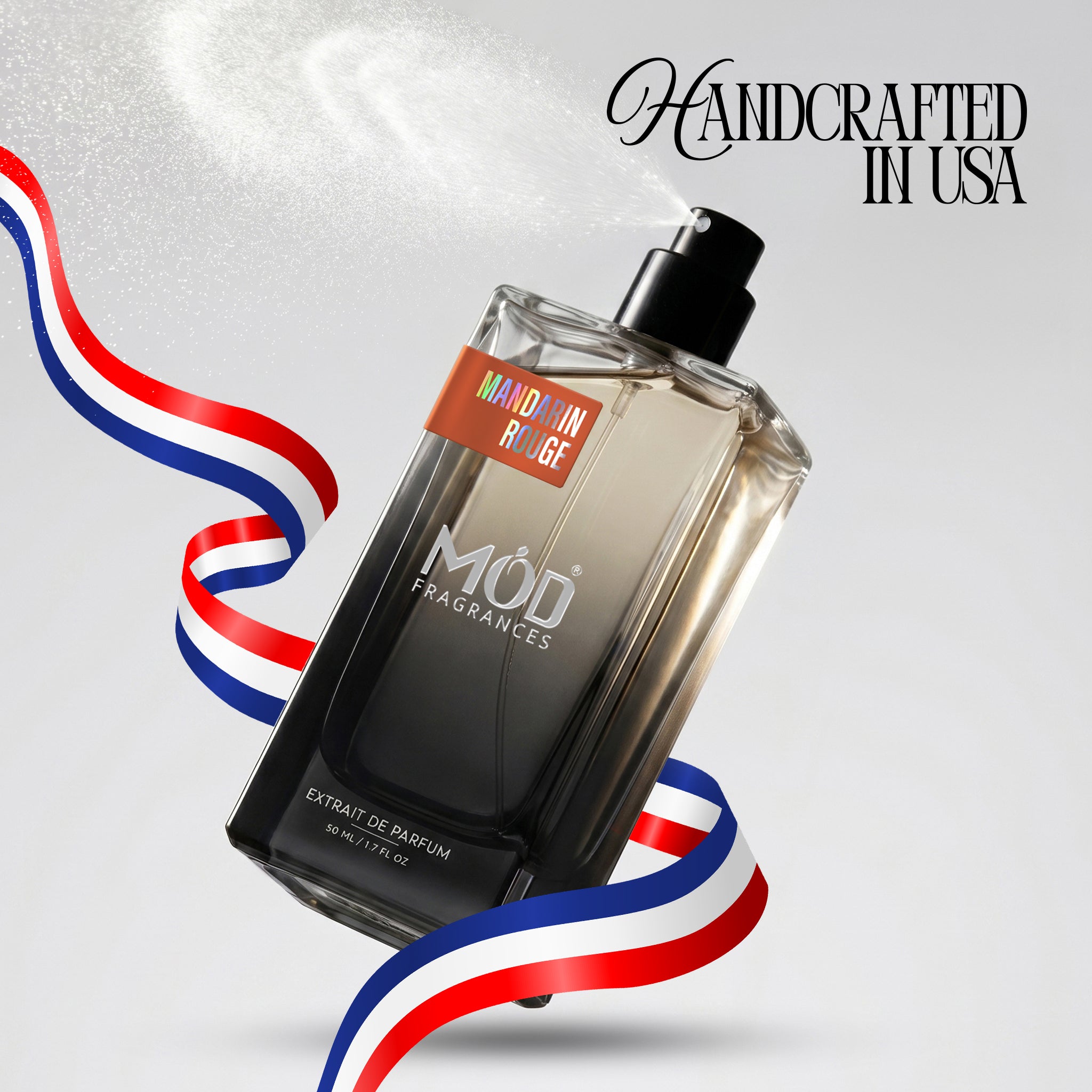 A bottle of MOD FRAGRANCES Extrait de Parfum with a black spray pump and a gradient amber-to-black glass body. The bottle is set against a light gray background with a white spray mist effect, accompanied by red, white, and blue ribbon graphics and the text 'Handcrafted in USA' and 'Made in France'.