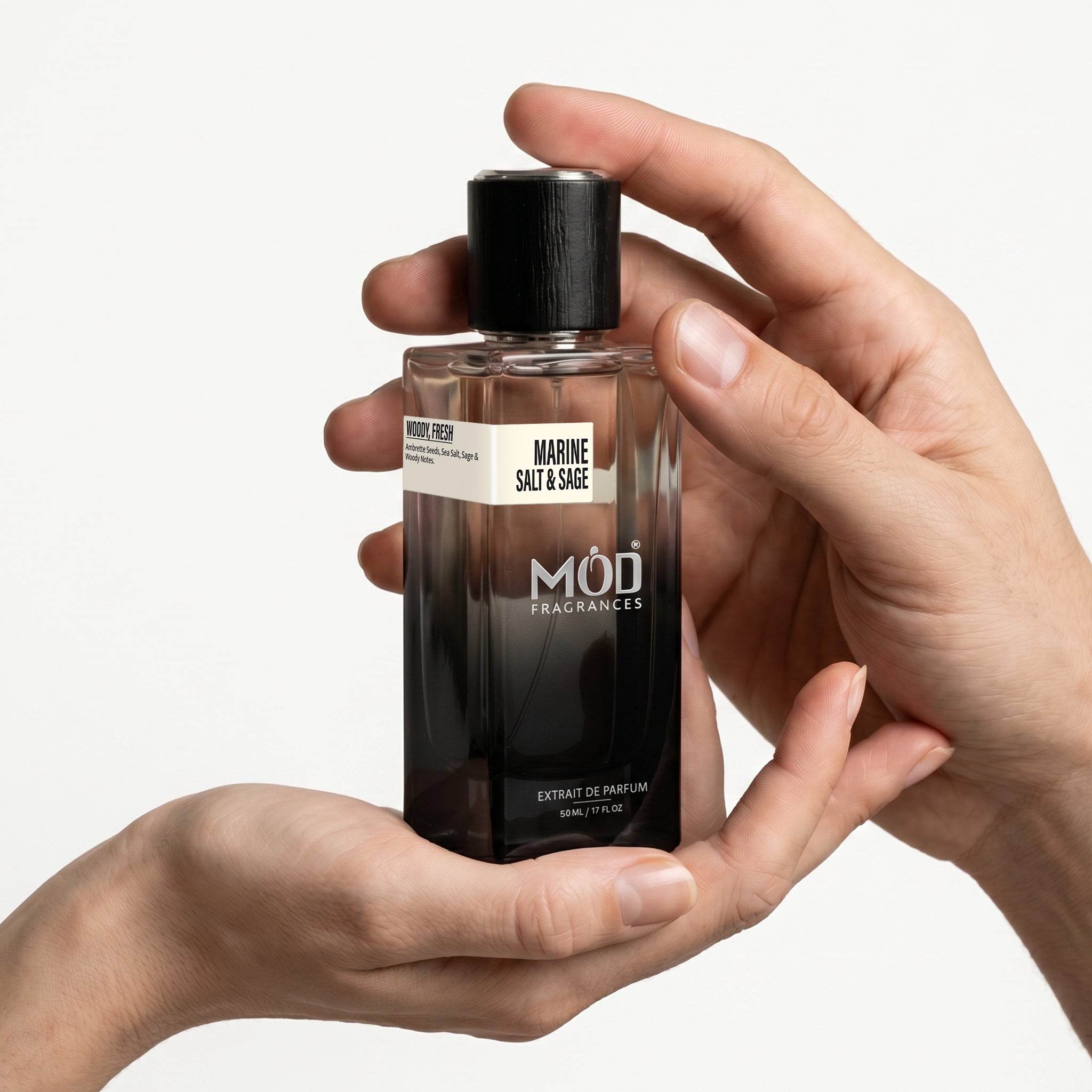 Person holding a MOD Fragrances perfume bottle with a plain background