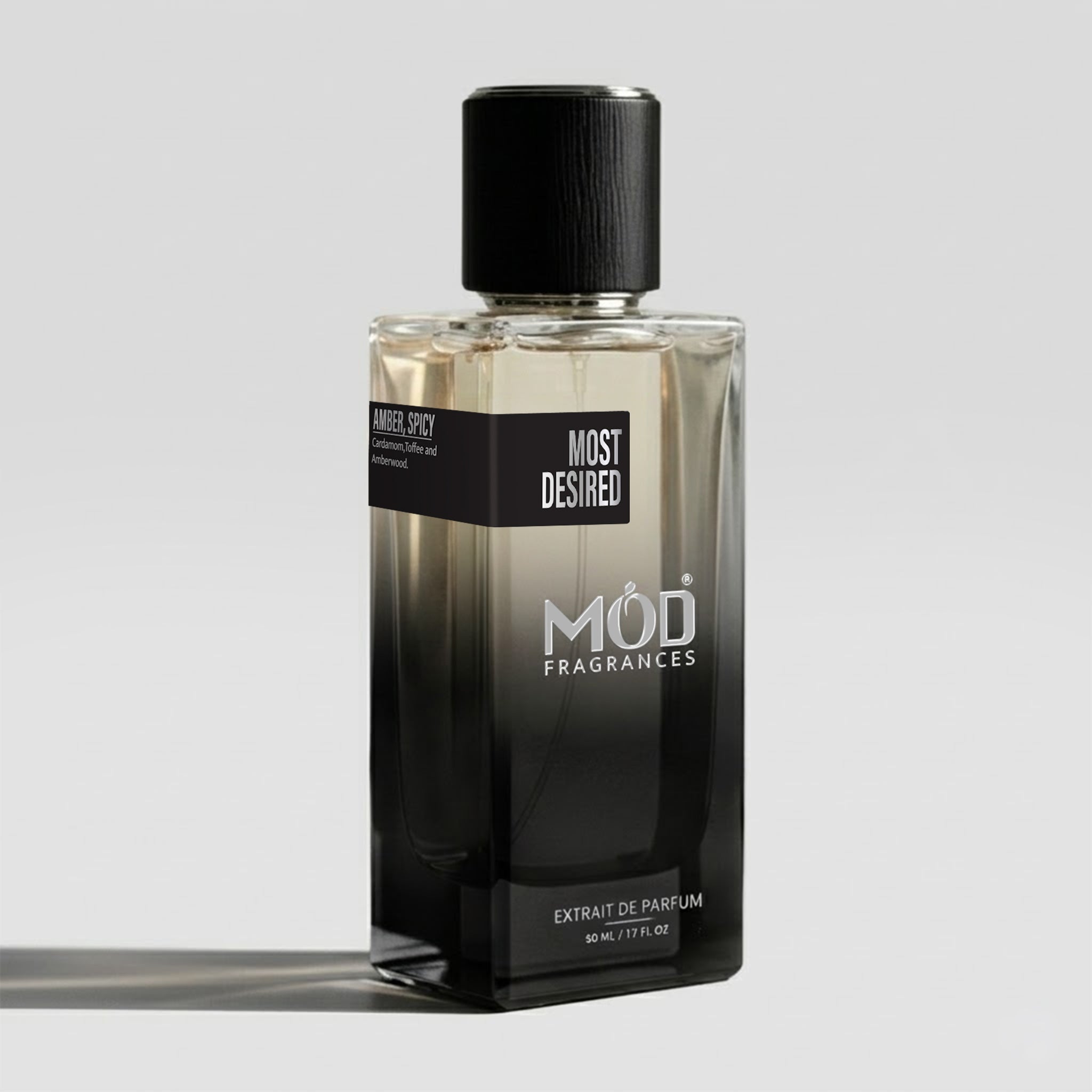 A rectangular glass perfume bottle by MOD Fragrances, labeled “Most Desired” with a small label detailing its notes, stands on a light background.