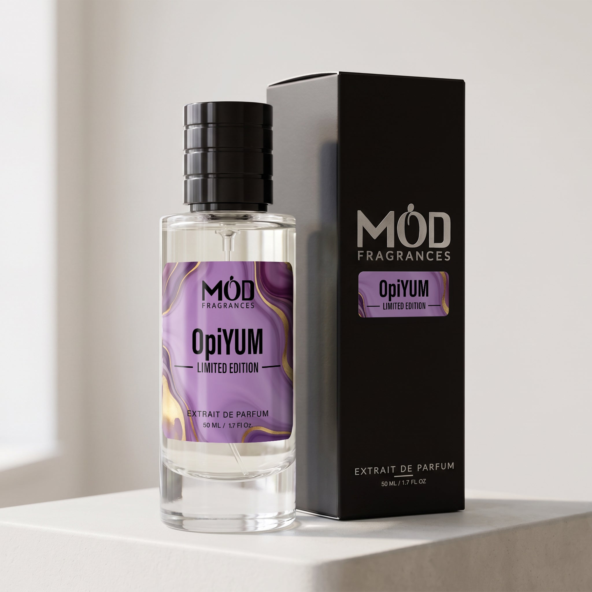 A clear glass perfume bottle with a black cap stands beside a tall black product box. The bottle and box both feature a purple marbled label reading 'MÓD FRAGRANCES' and 'OpiYUM L’IMITÉD EDITION'.