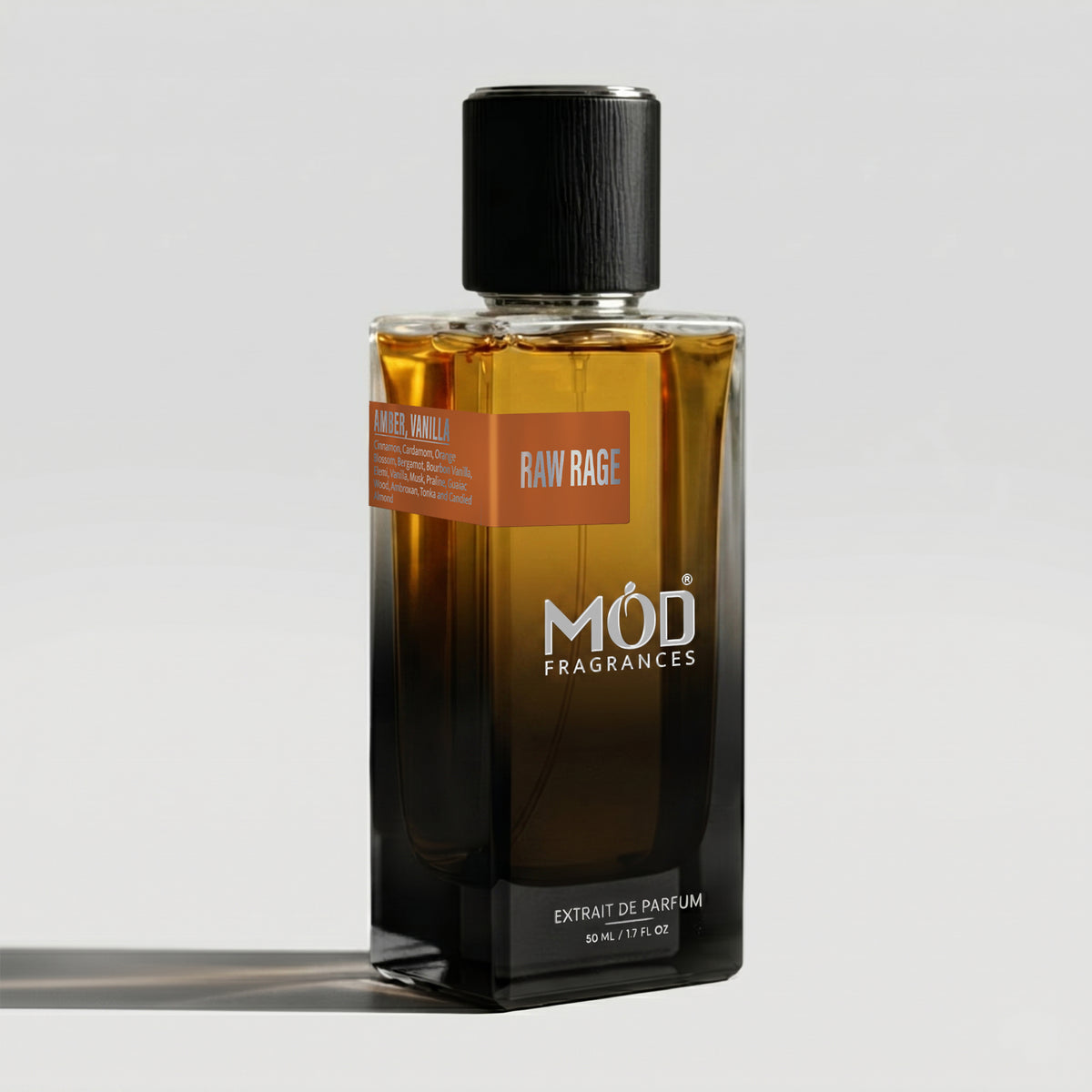 A rectangular glass perfume bottle by MOD Fragrances, labeled “Raw Rage” with a small label detailing its notes, stands on a light background.