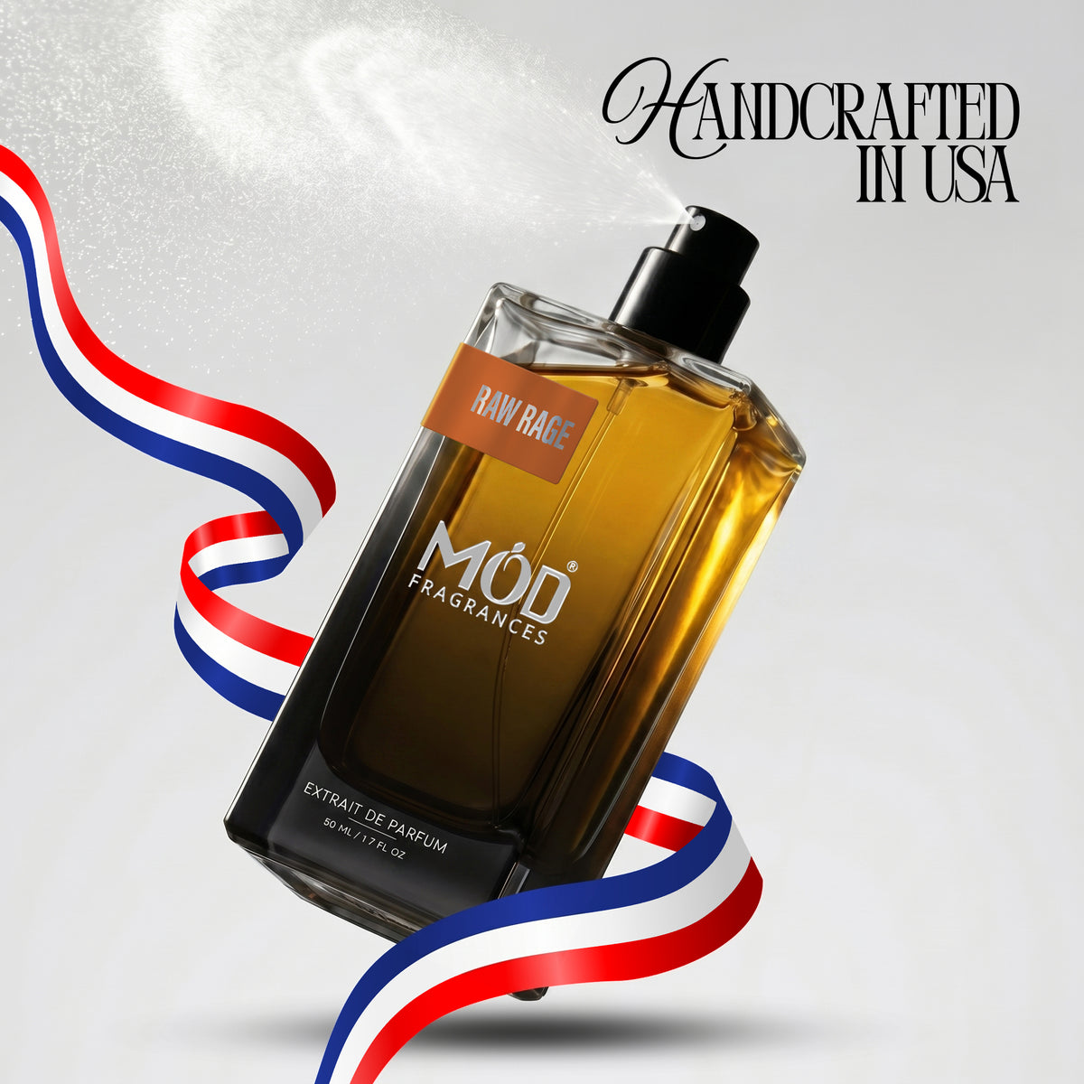 A rectangular glass perfume bottle by MOD Fragrances, labeled "Raw Rage” is captured mid-spray with a fine mist dispersing into the air, accented by stylized red, white, and blue ribbons, with the text "Handcrafted in USA" in the upper right.
