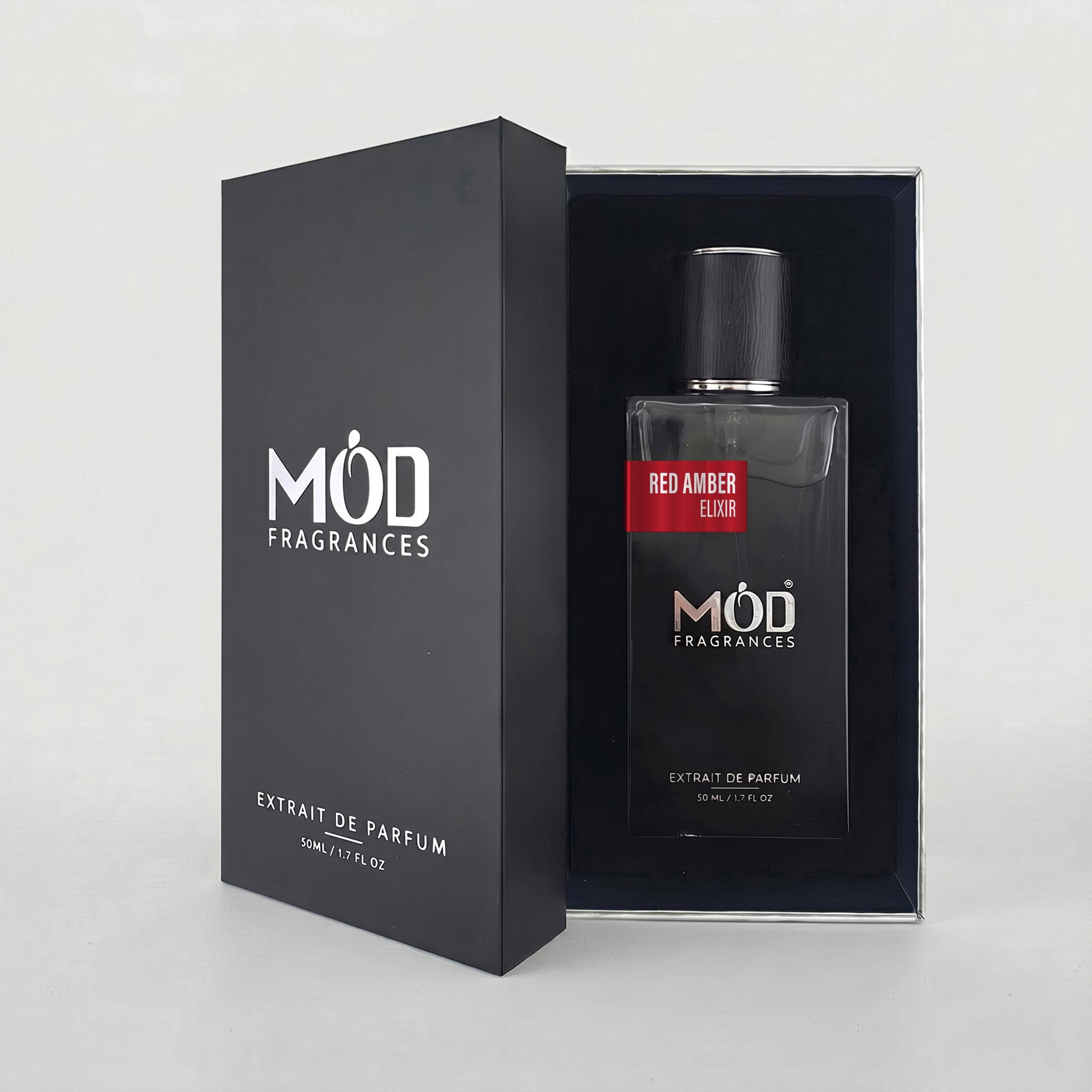 An open black perfume box reveals a rectangular glass bottle labeled "Red Amber Elixir" by MOD Fragrances, resting securely in a black-lined presentation case. 