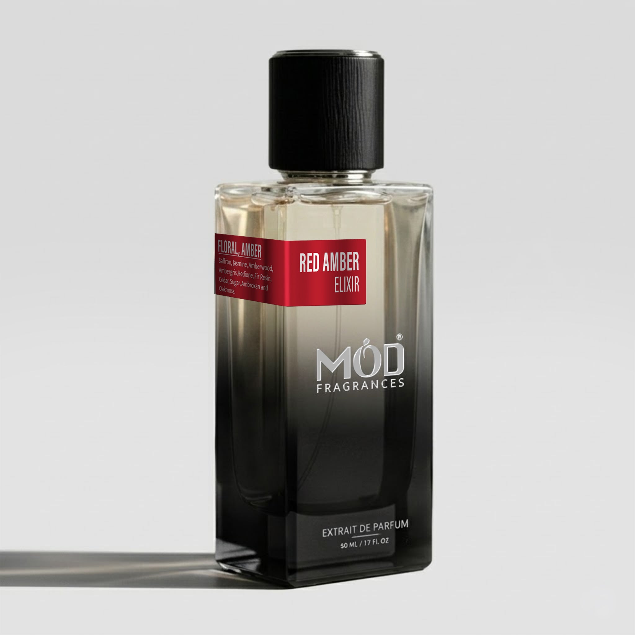 A rectangular glass perfume bottle by MOD Fragrances, labeled "Red Amber Elixir" with a small label detailing its leather, woody notes, stands on a light background.