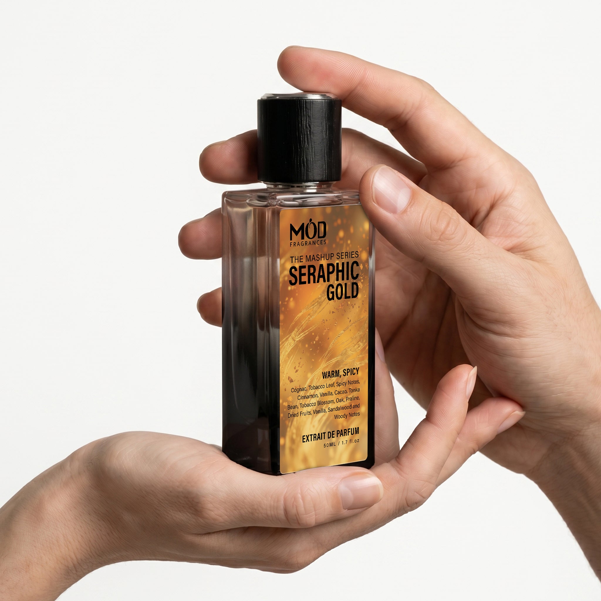A male & Female person's hand holds a rectangular glass perfume bottle by MOD Fragrances, labeled "Mashup series Seraphic Gold" against a plain white background.
