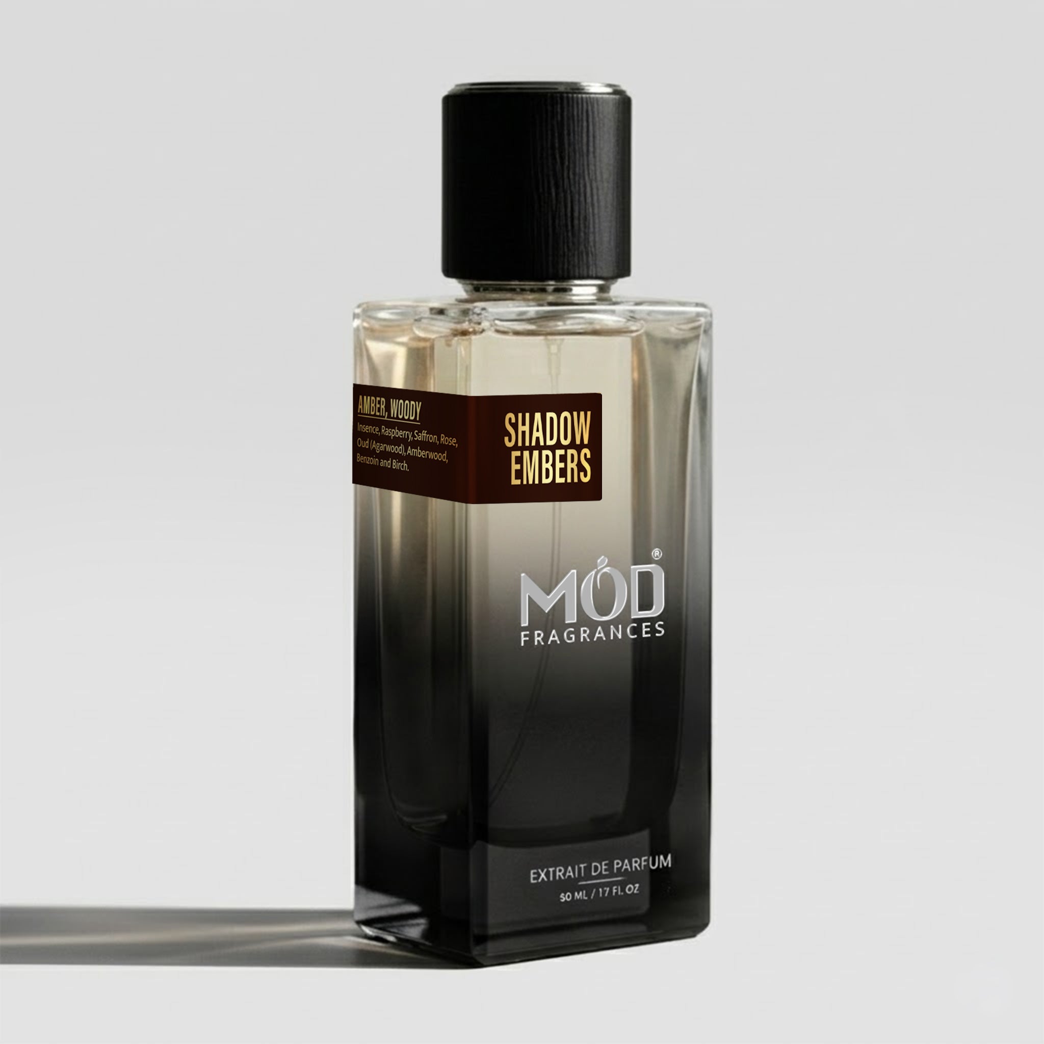 A rectangular glass perfume bottle by MOD Fragrances, labeled “Shadow Embers” with a small label detailing its notes, stands on a light background.