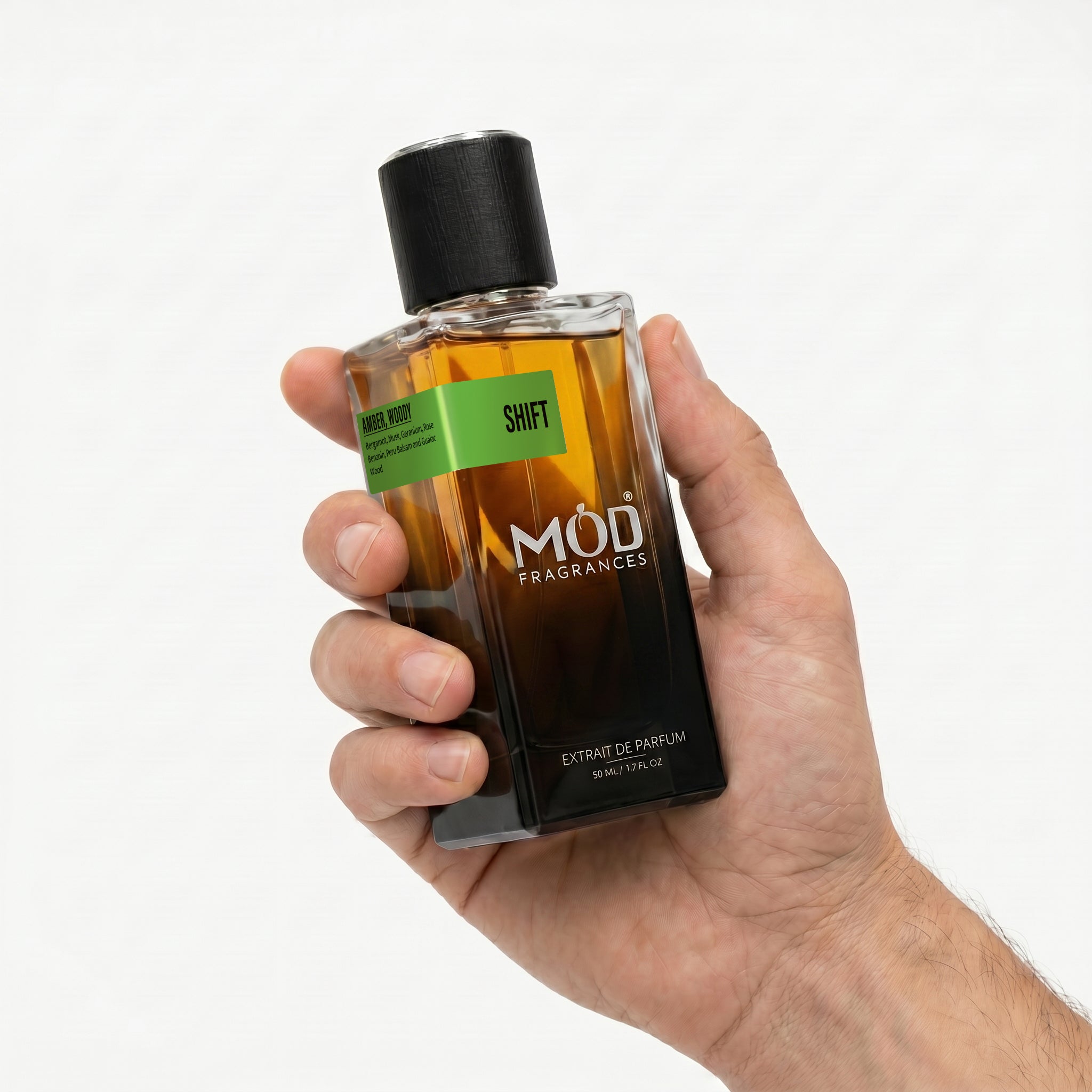 A male person's hand holds a rectangular glass perfume bottle by MOD Fragrances, labeled "Shift" against a plain white background.