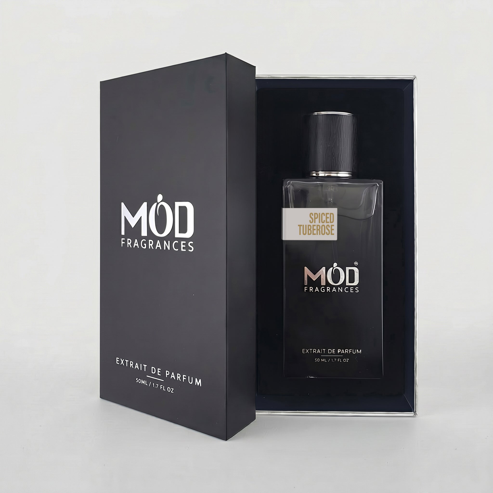 An open premium black perfume box reveals a rectangular glass bottle labeled “Spiced Tuberose” by MOD Fragrances, resting securely in a black-lined presentation case. 
