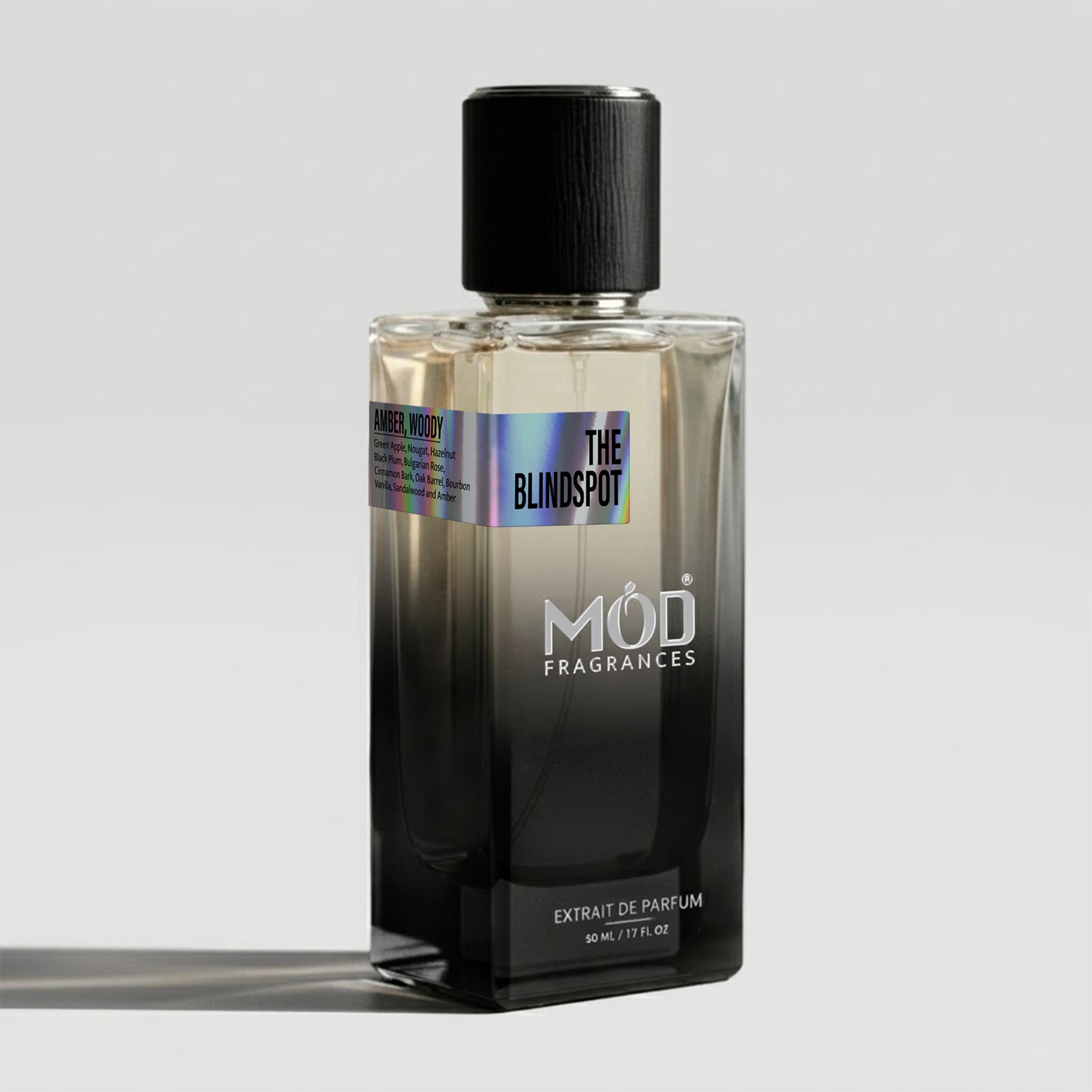 A rectangular glass perfume bottle by MOD Fragrances, labeled "The Blindspot" with a small label detailing its fresh, aromatic notes, stands on a light background.