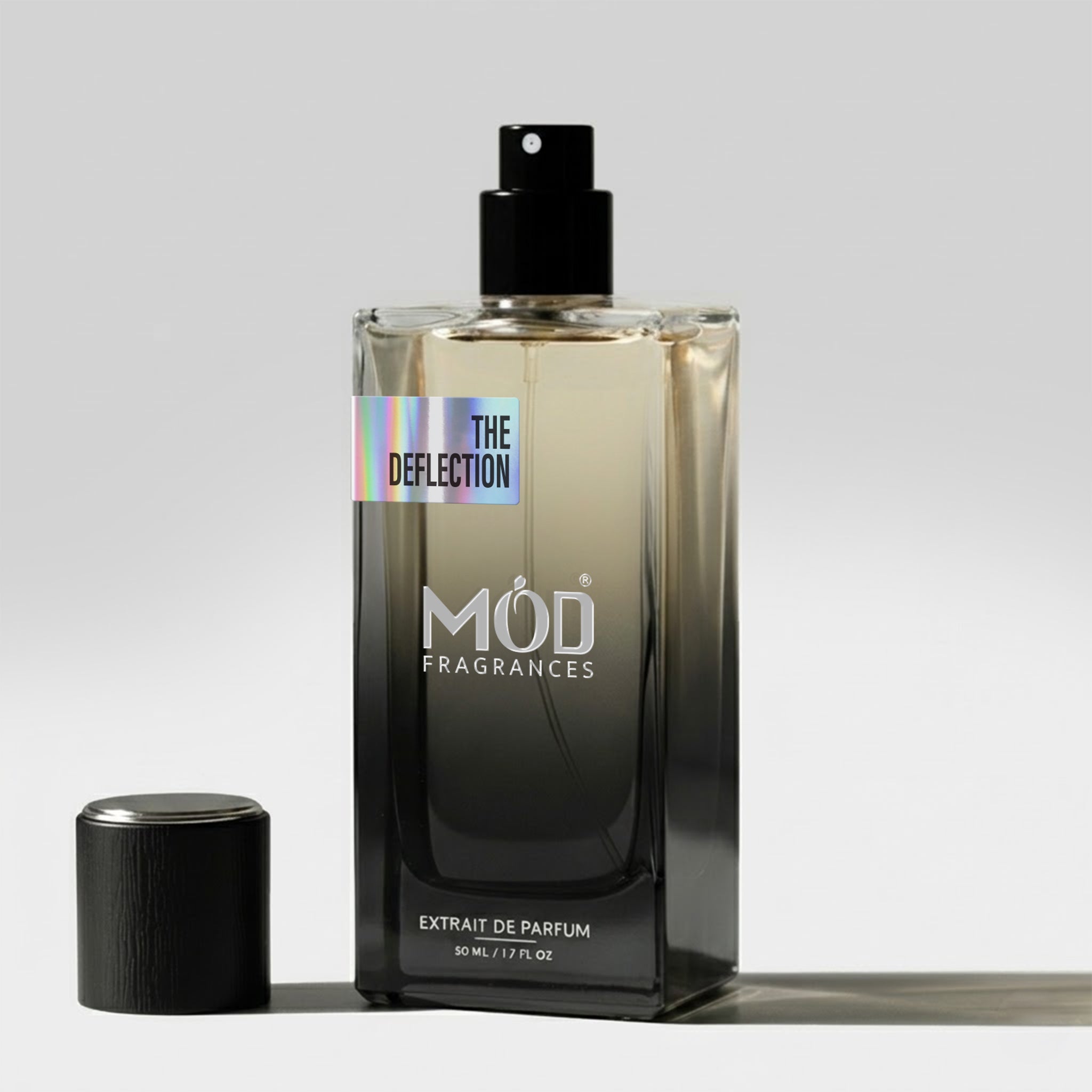 A bottle of Mod Fragrances 'The Deflection' extrait de parfum next to its cap on a light gray background.