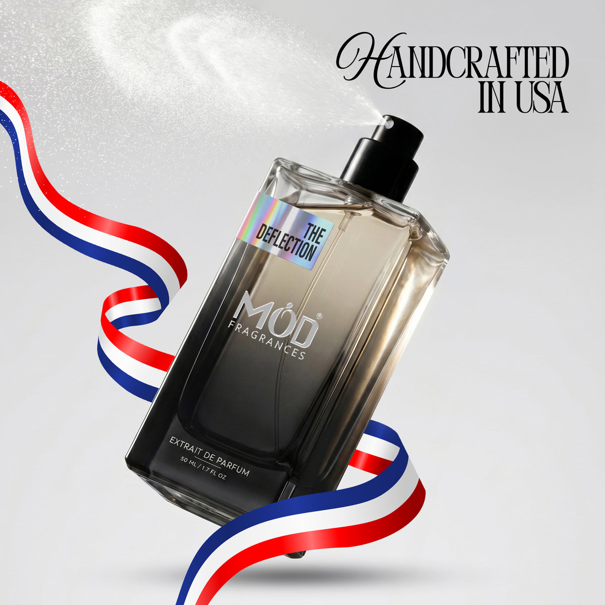 A bottle of Mod Fragrances 'The Deflection' eau de parfum floating diagonally on a light gray background with a white spray mist. The bottle is clear glass showing a dark amber liquid inside, with a black spray nozzle.