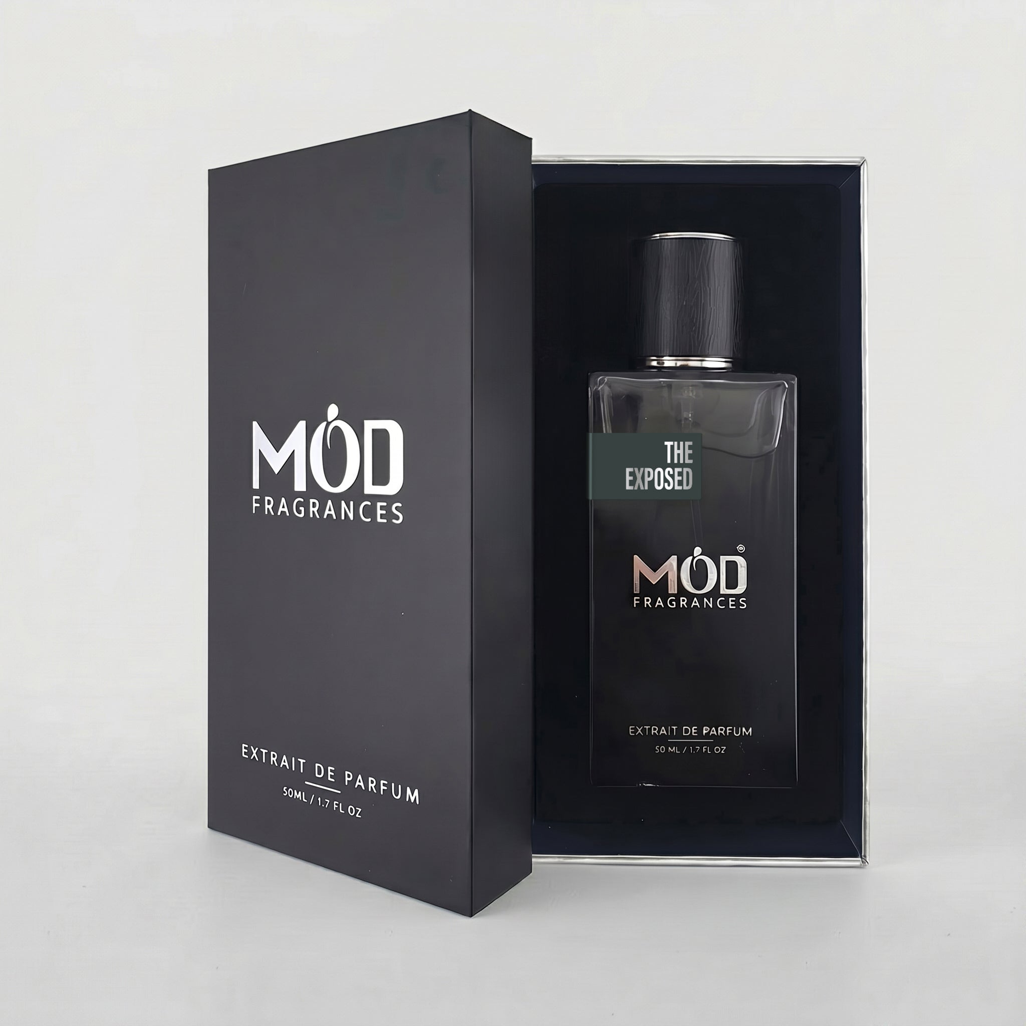 An open black perfume box reveals a rectangular glass bottle labeled "The Exposed" by MOD Fragrances, resting securely in a black-lined presentation case.