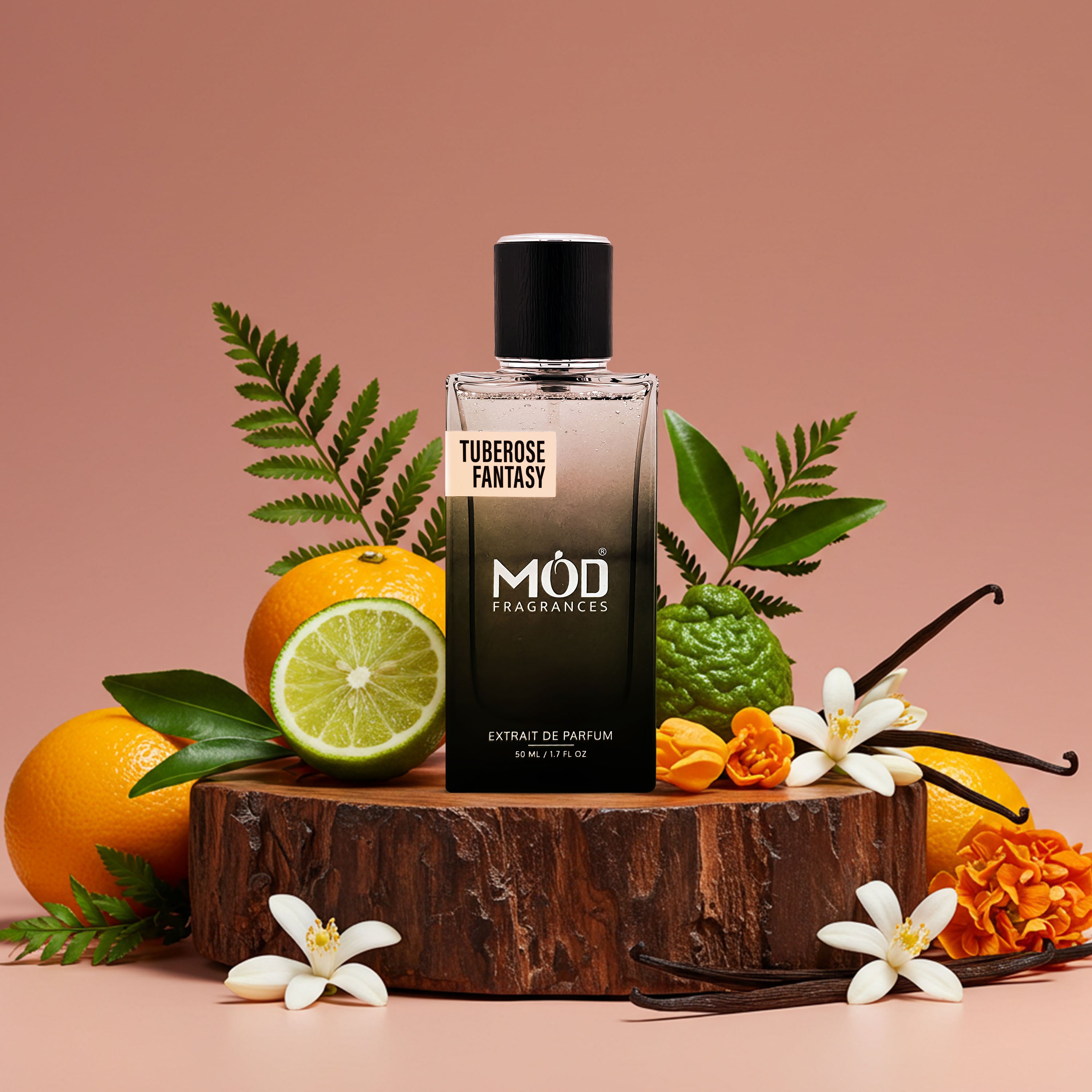 A bottle of Tuberoso Fantasy Extrait de Parfum by Mód Fragrances, styled on a rustic wood slice pedestal with oranges, a lime, vanilla beans, and white flowers against a solid dusty rose background.