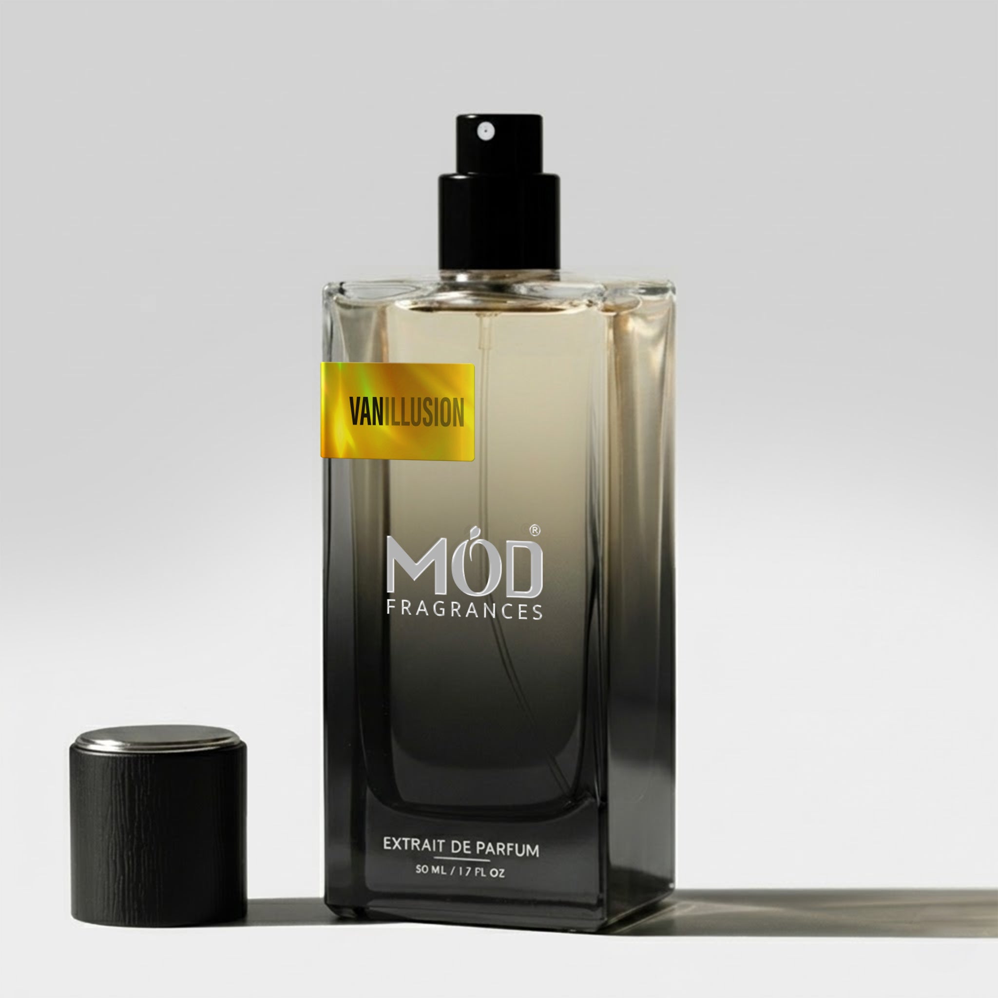 A bottle of Mod Fragrances Vanillusion Extrait de Parfum with a black spray top and a yellow label, shown next to its black cap on a light gray background.