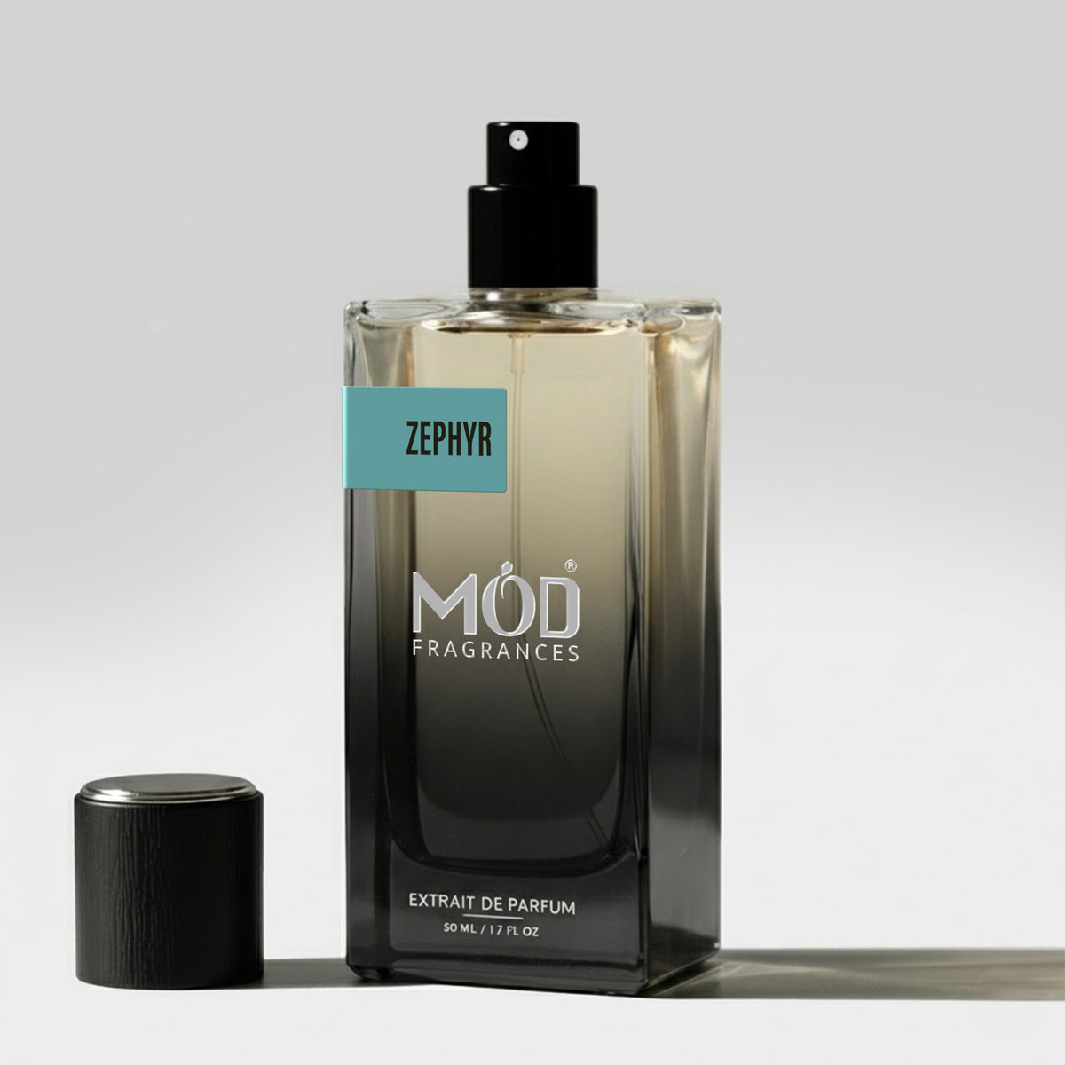 A rectangular glass perfume bottle by MOD Fragrances, labeled "Zephyr” stands on a light surface with its black cap placed beside it.