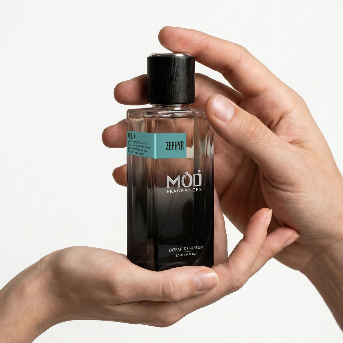 A Male and a female person's hands holds a rectangular glass perfume bottle by MOD Fragrances, labeled "Zephyr” against a plain white background.